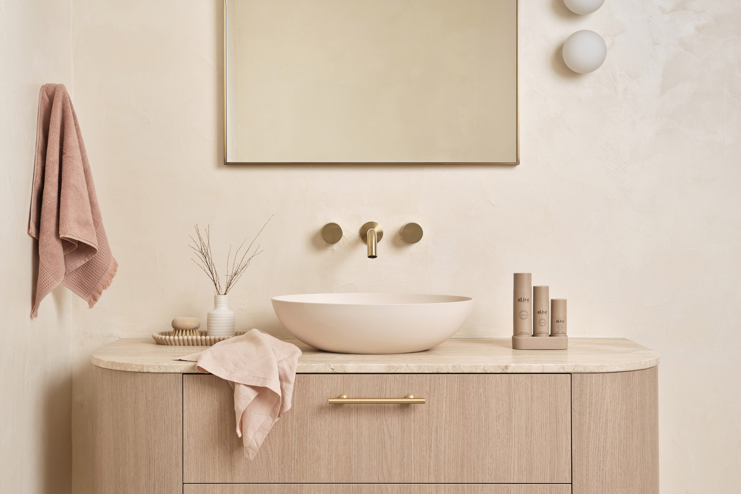 Minimalist bathroom with a carved wood cabinet, a white vessel sink, beige towels, and neutral decor