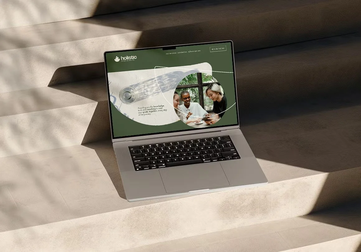 Open laptop on concrete steps, displaying a website with a green header and an image of three diverse women smiling and looking at a device.