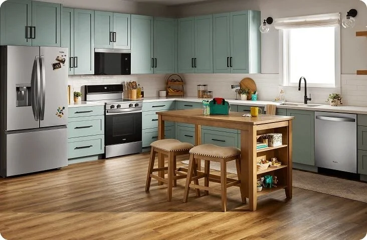 Modern kitchen with light blue cabinets, a stainless steel refrigerator, black and silver stove, white subway tile backsplash, wooden kitchen island with stools, and various kitchen items near a window.
