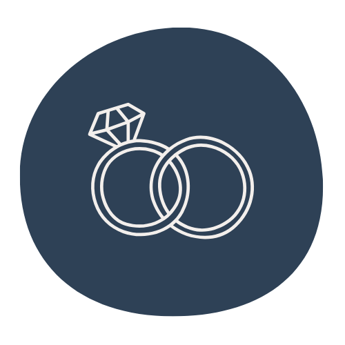 Icon of two wedding rings and a diamond, all outlined in white on a dark blue circular background.