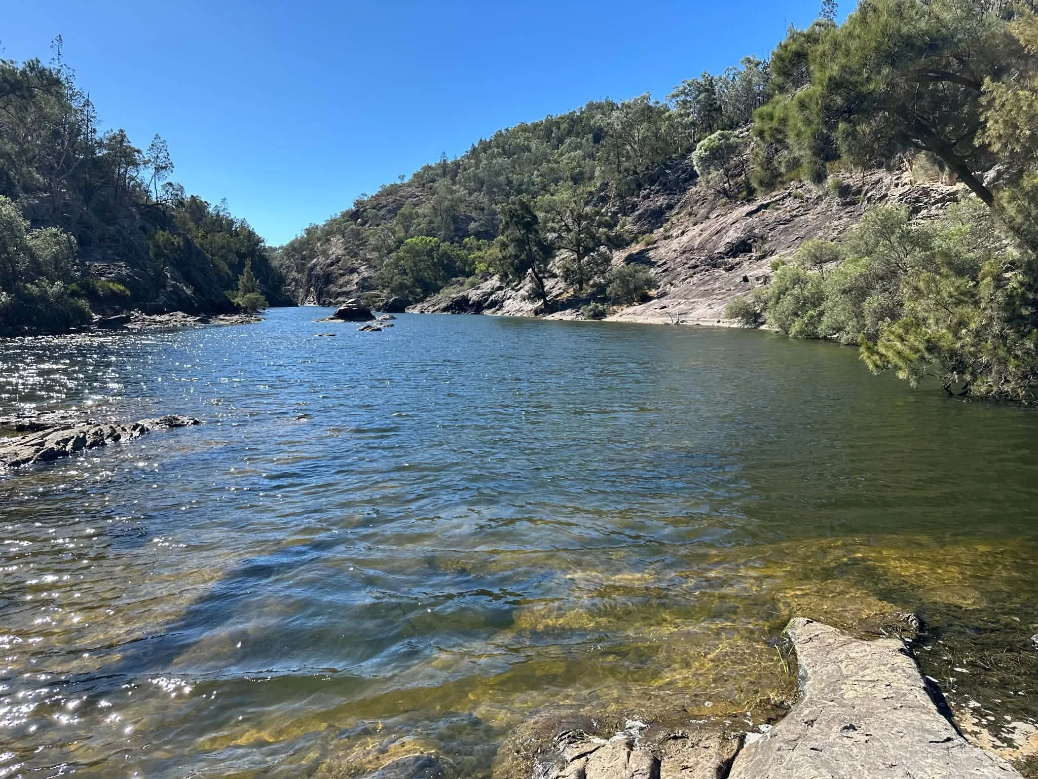 Severn River flowing between rocky hills covered with trees under a bright blue sky.