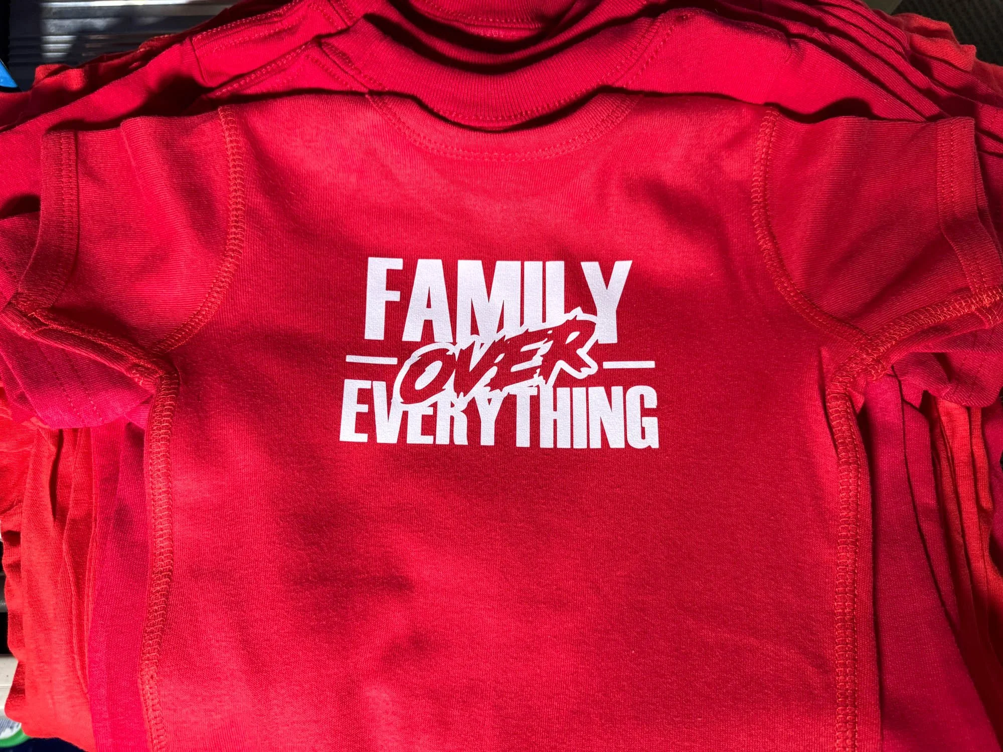 Red T-shirt with bold white text that reads "Family Over Everything" and the word "Over" stylized as a handwritten overlay.