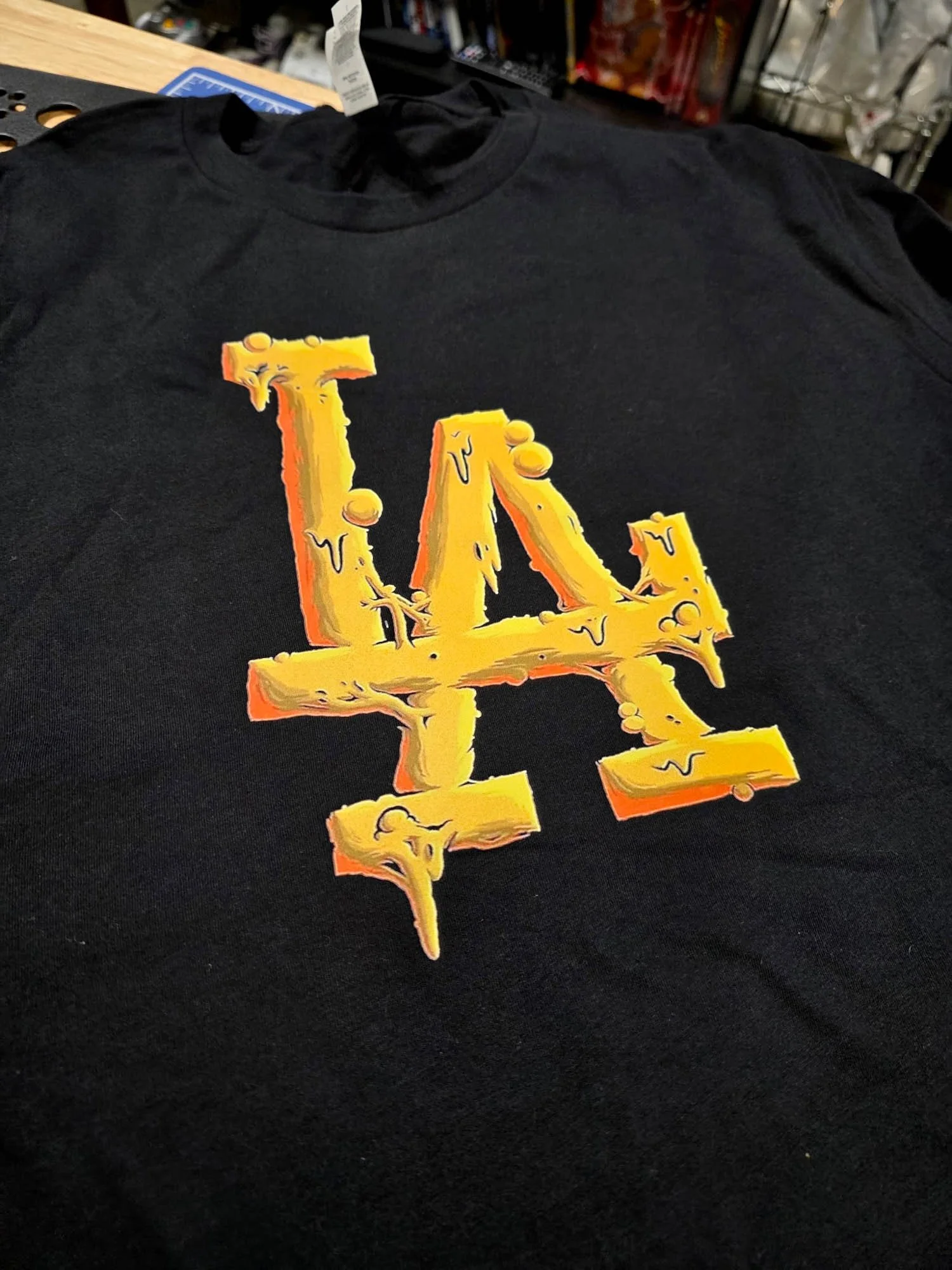 Black t-shirt with a yellow LA Dodgers logo that appears to be melting or dripping.
