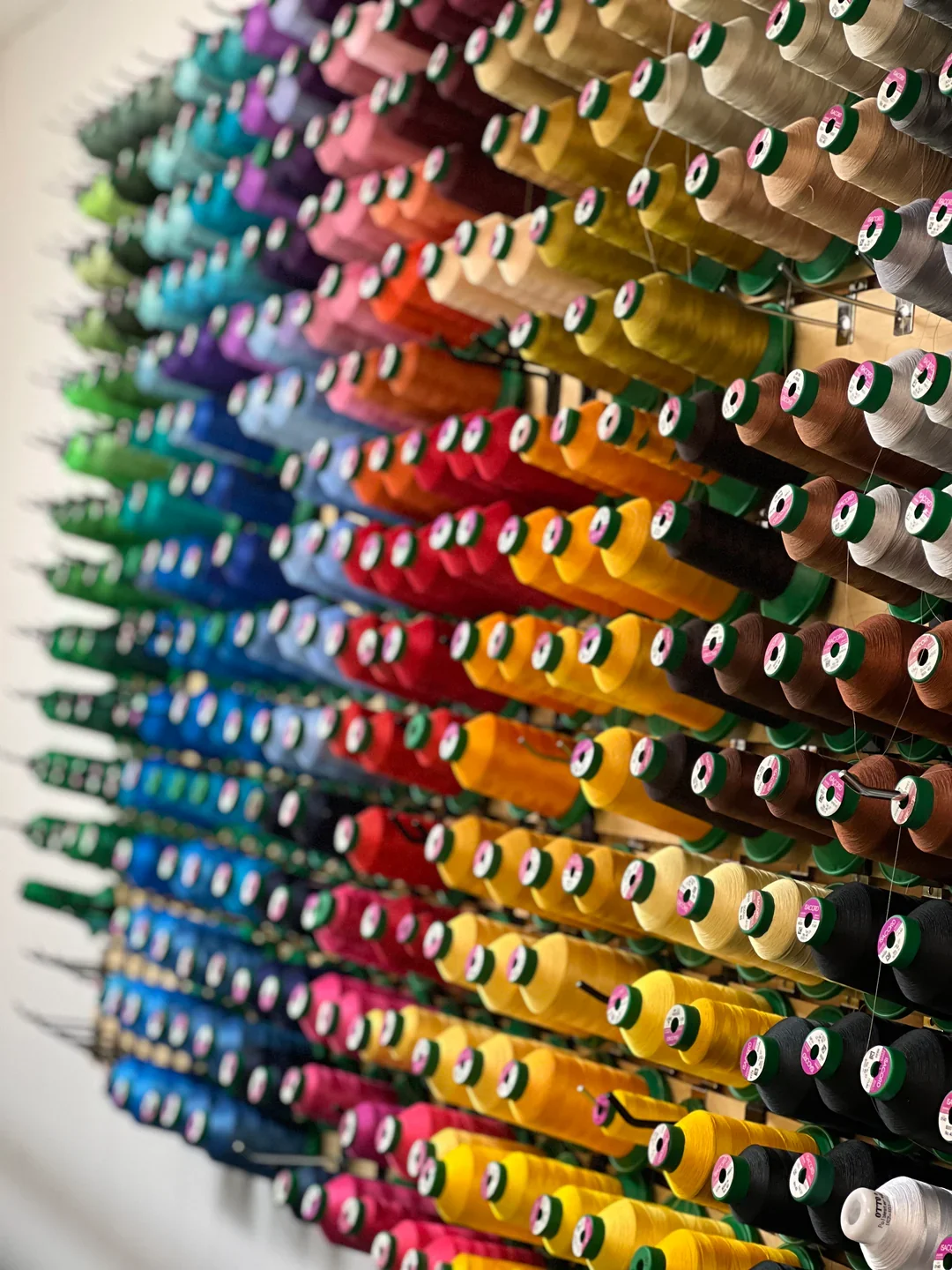 Colorful spools of thread arranged on a display rack in a store.
