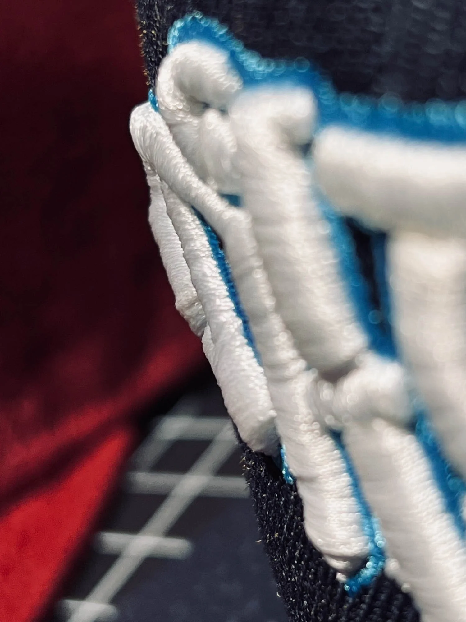 Close-up of embroidered white and blue thread on a black fabric surface.