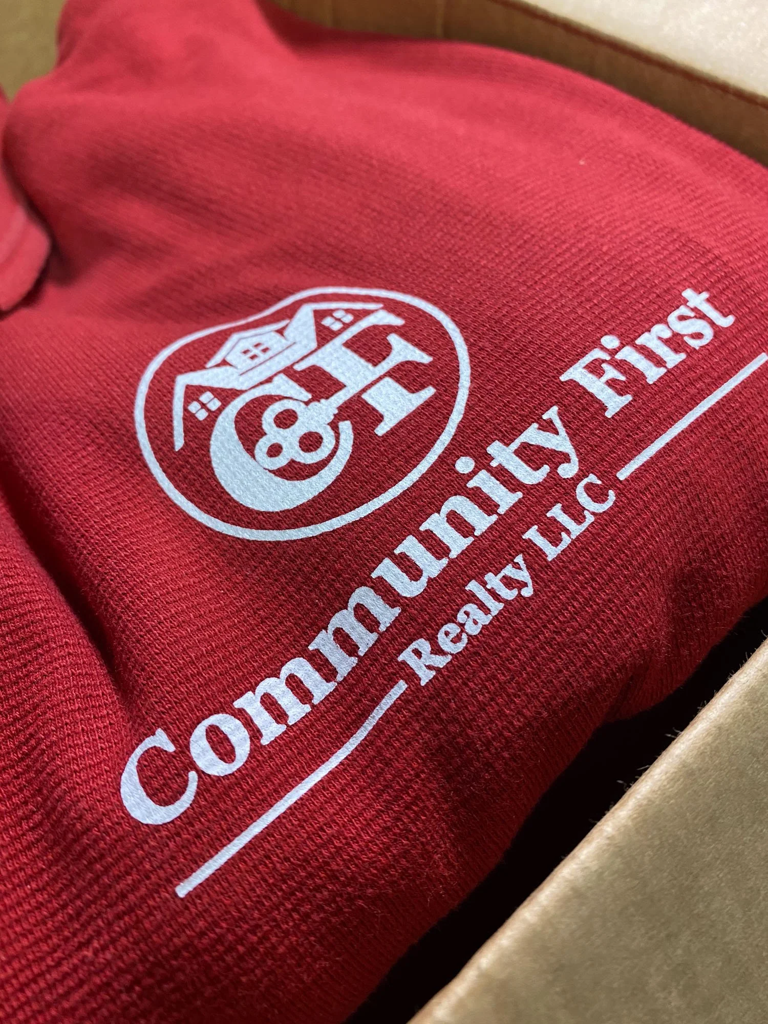 Close-up of a red fabric with a white logo and text that reads 'Community First Realty LLC'.