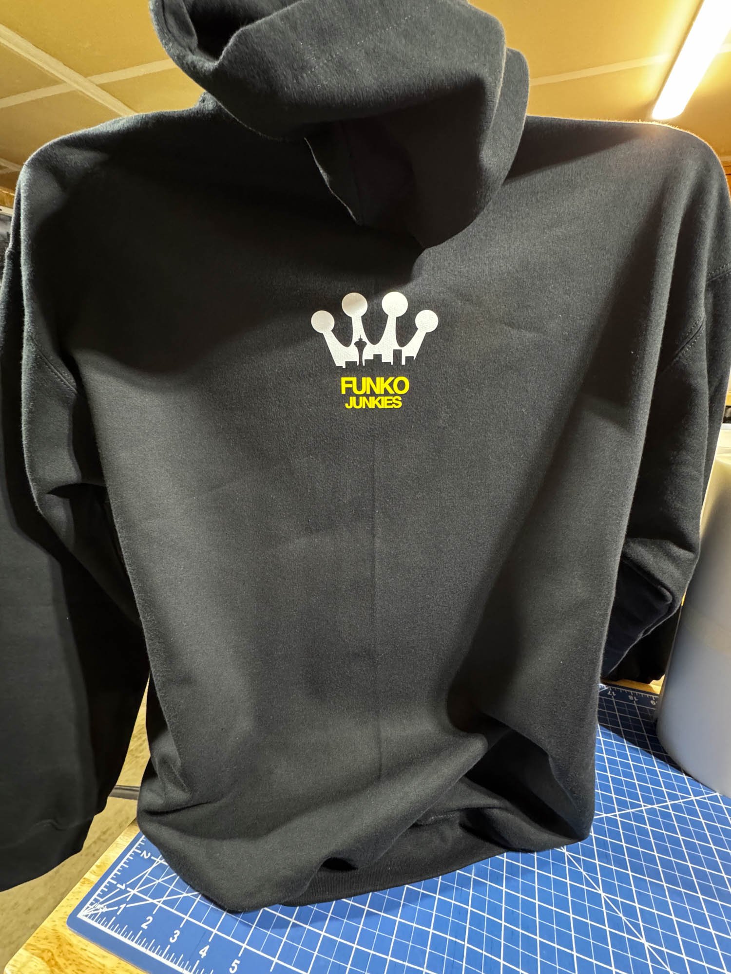 Black hoodie featuring a white crown logo and yellow text that says 'FUNKO JUNKIES', displayed on a mannequin.