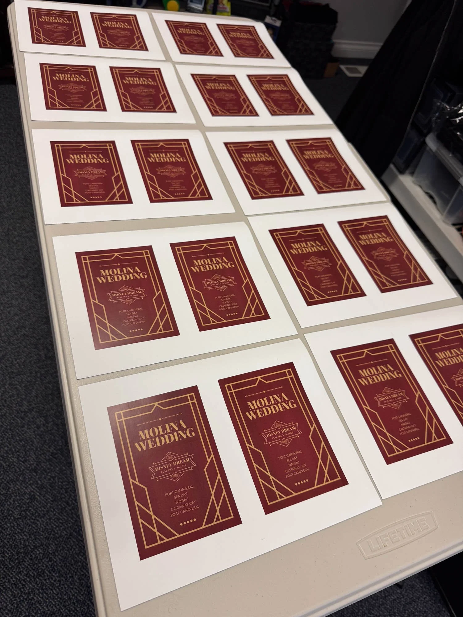 Multiple copies of a red and gold wedding invitation card arranged on a table.