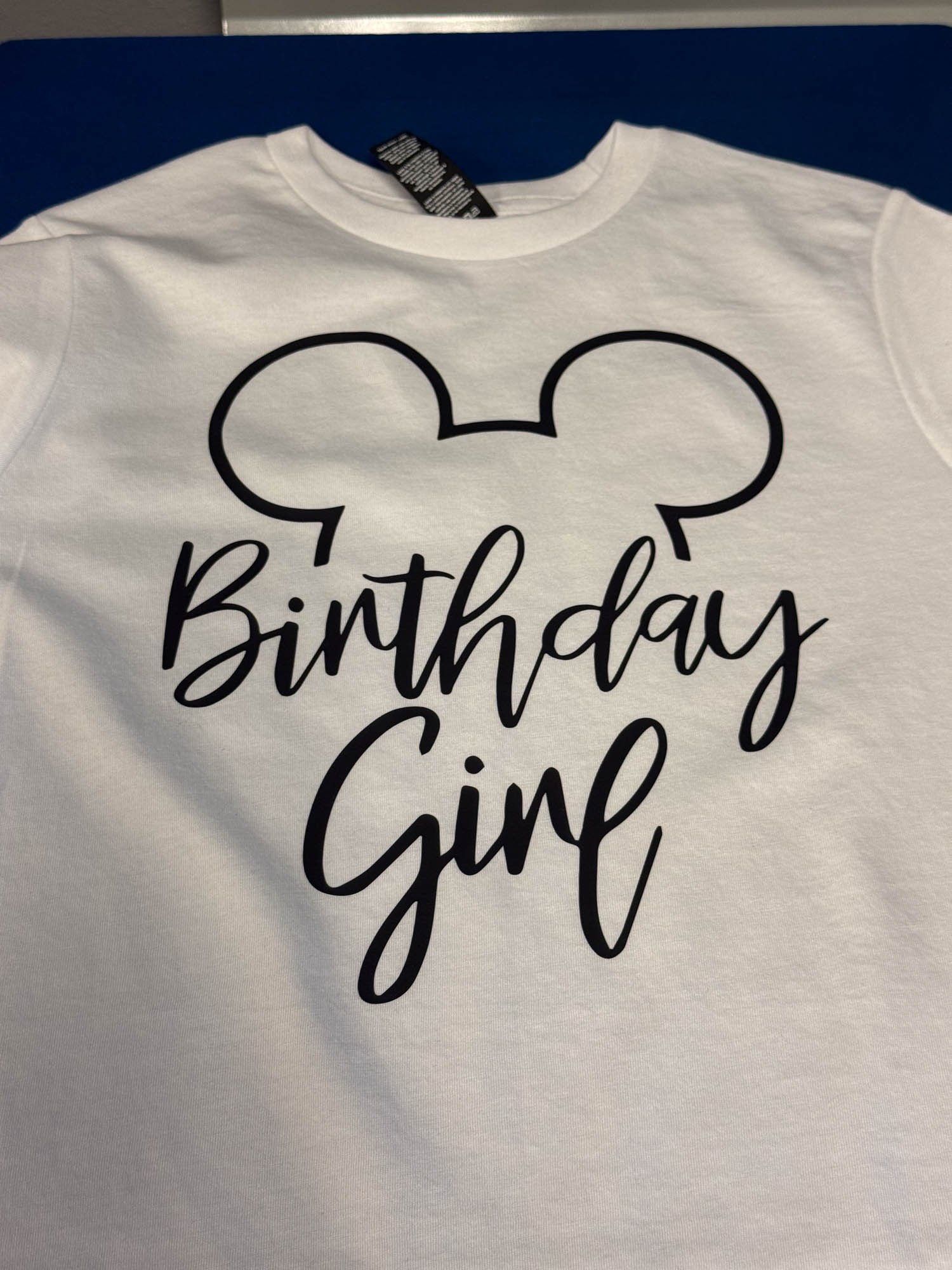 White birthday girl shirt with a black outline of Mickey Mouse ears and the words 'Birthday Girl' in black cursive font.