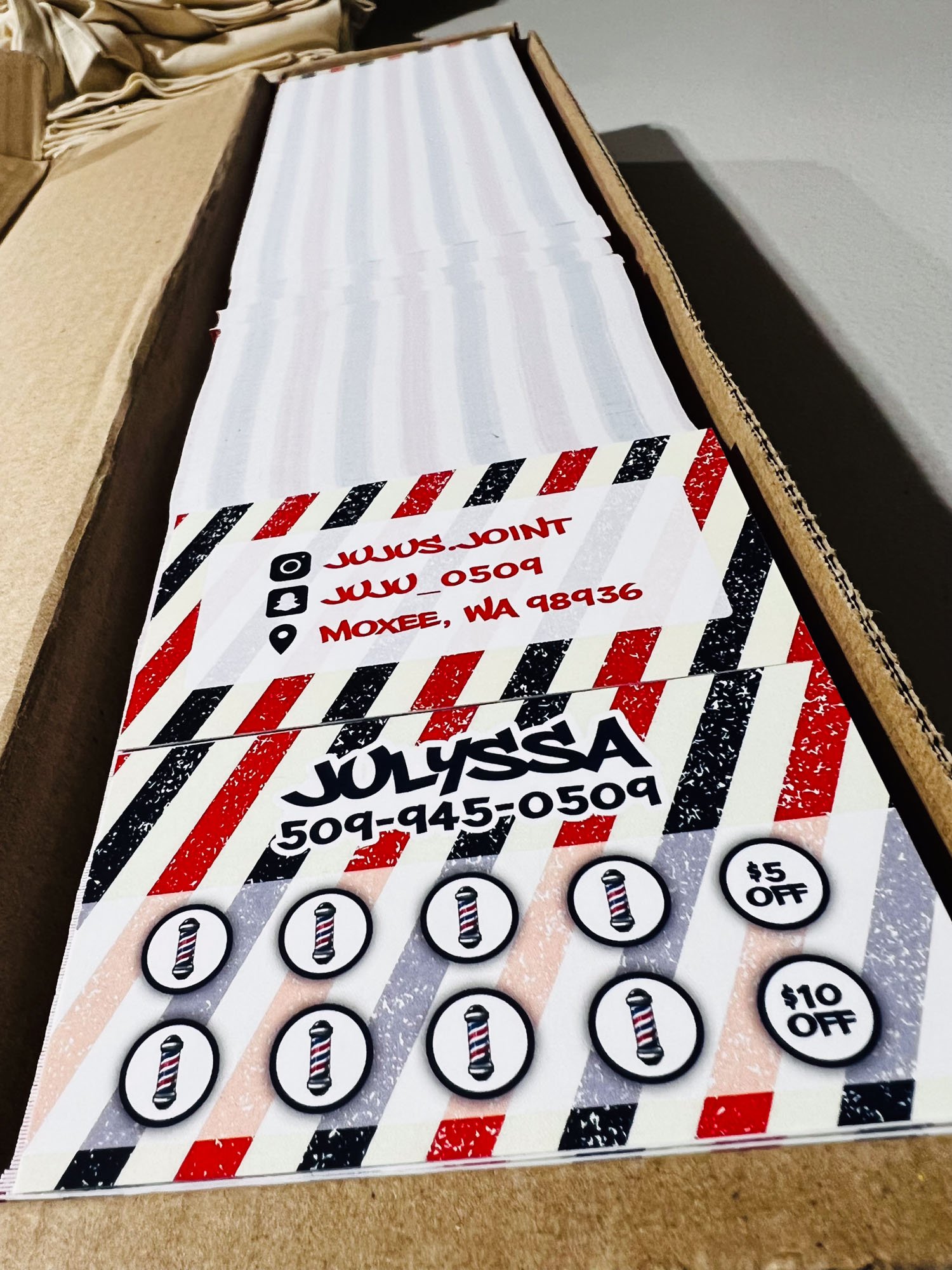 Business cards for JULYSSA with contact information and discount coupons, placed on a cardboard surface.