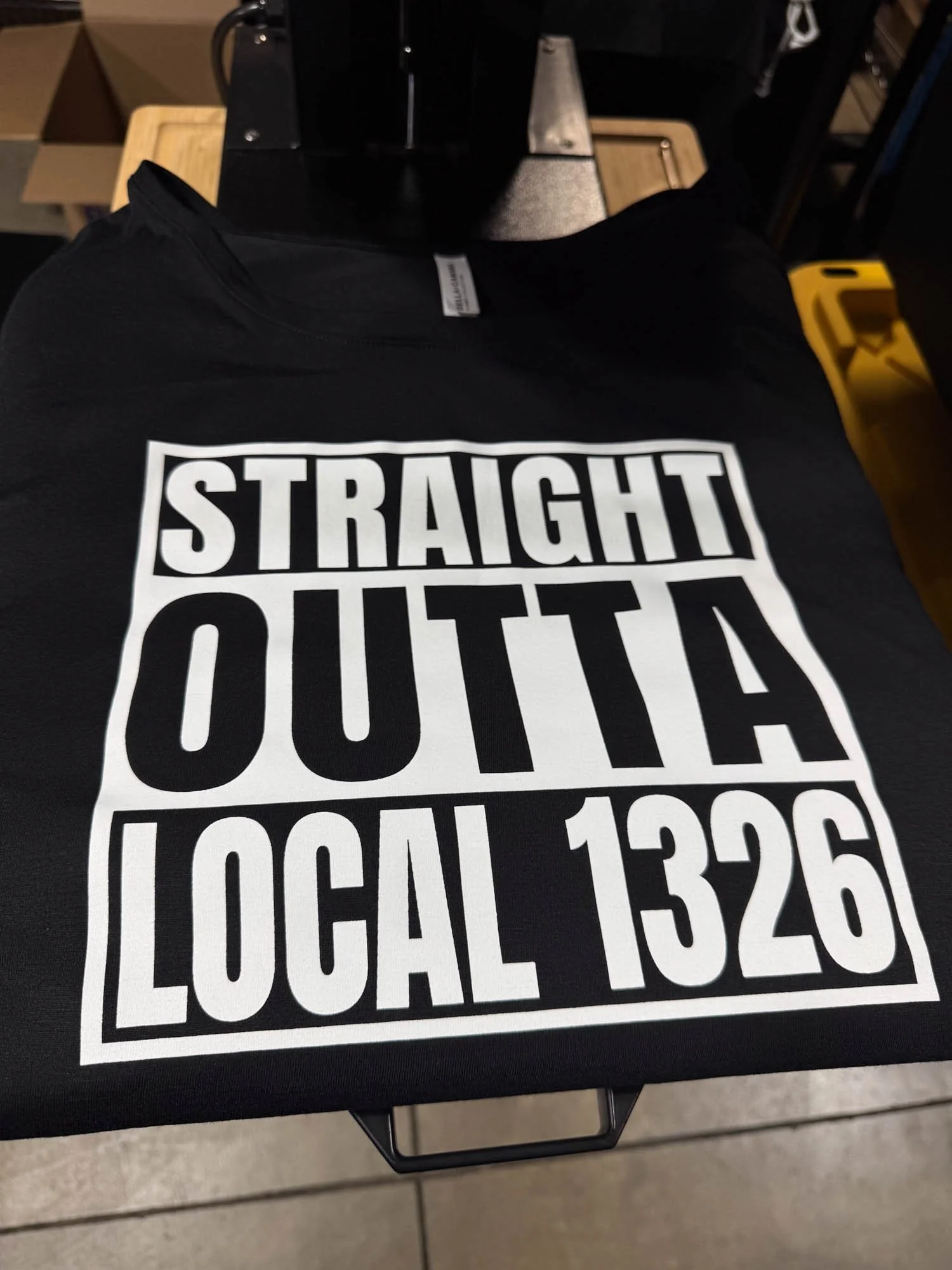 Black T-shirt with bold white text that reads 'Straight Outta Local 1326' laid on a surface.