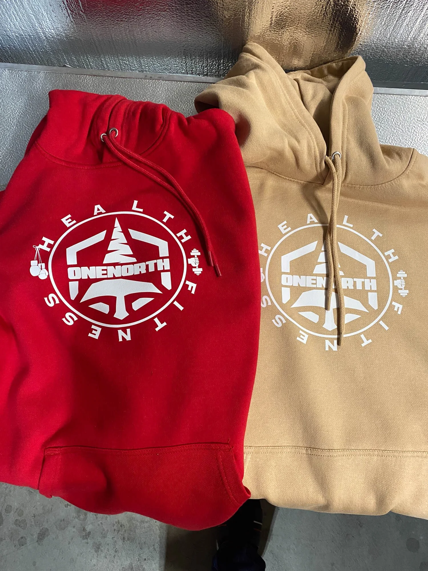Red and beige hoodies with the same 'Onboard' logo and text, placed on a flat surface.