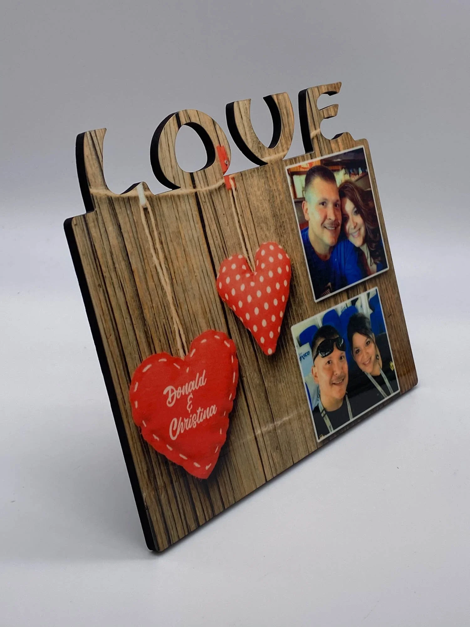Decorative photo frame with the word 'LOVE' at the top, two plush hearts, and two photographs of a couple, one at the top right and one at the bottom right.