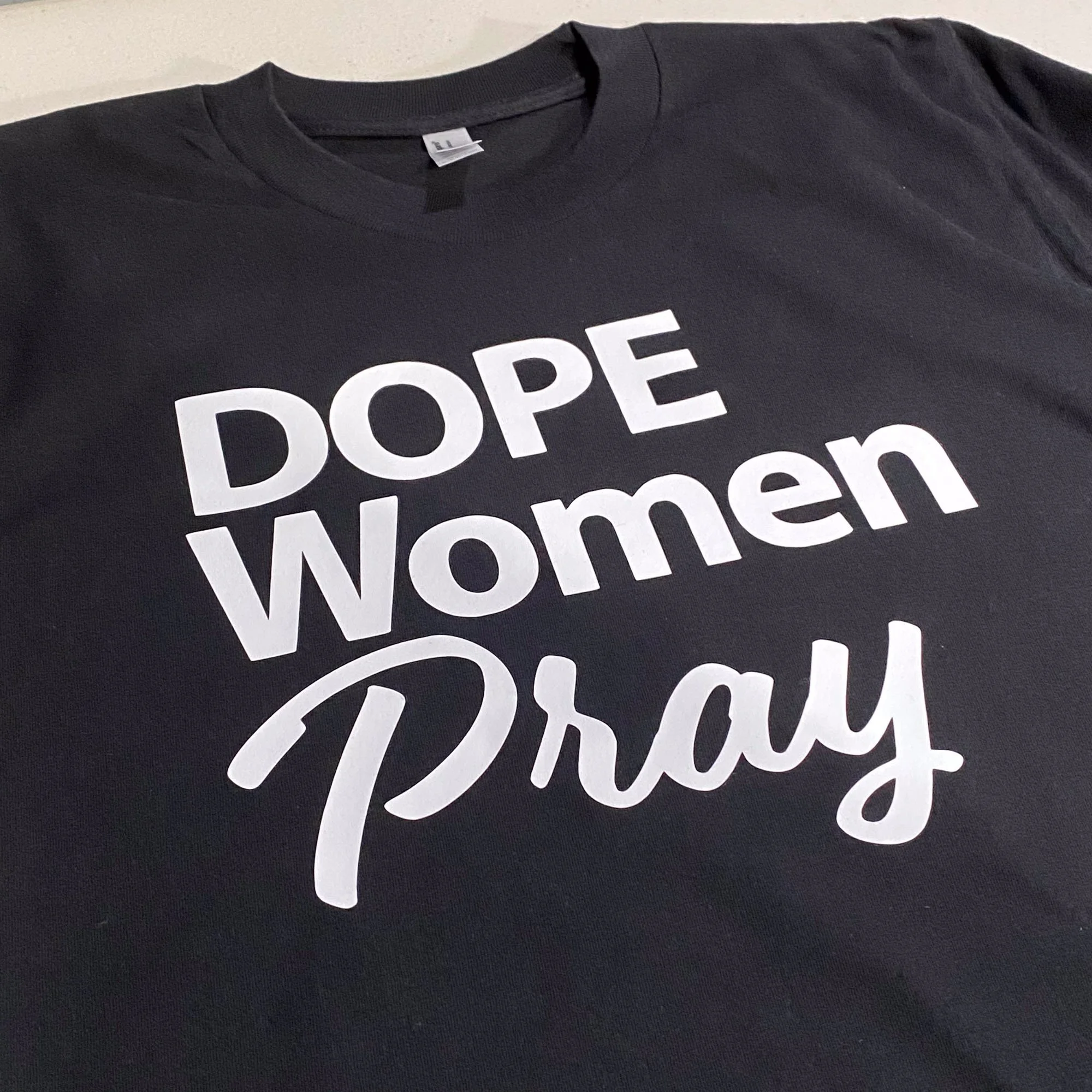 Black T-shirt with white text reading 'DOPE Women Pray'.