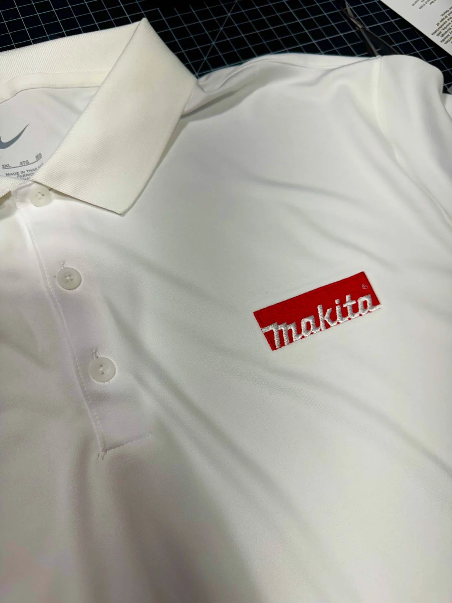 White polo shirt with a red and white Makita logo embroidery on the left chest area.