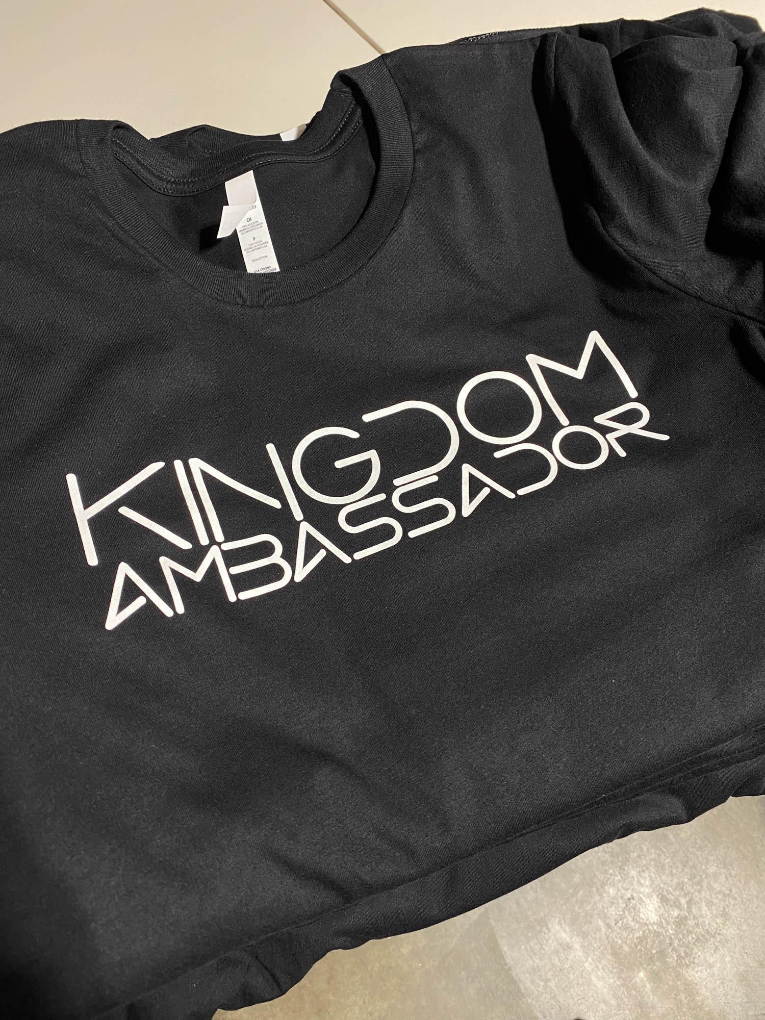 Black T-shirt with white text that reads 'KINGDOM AMBASSADOR'.