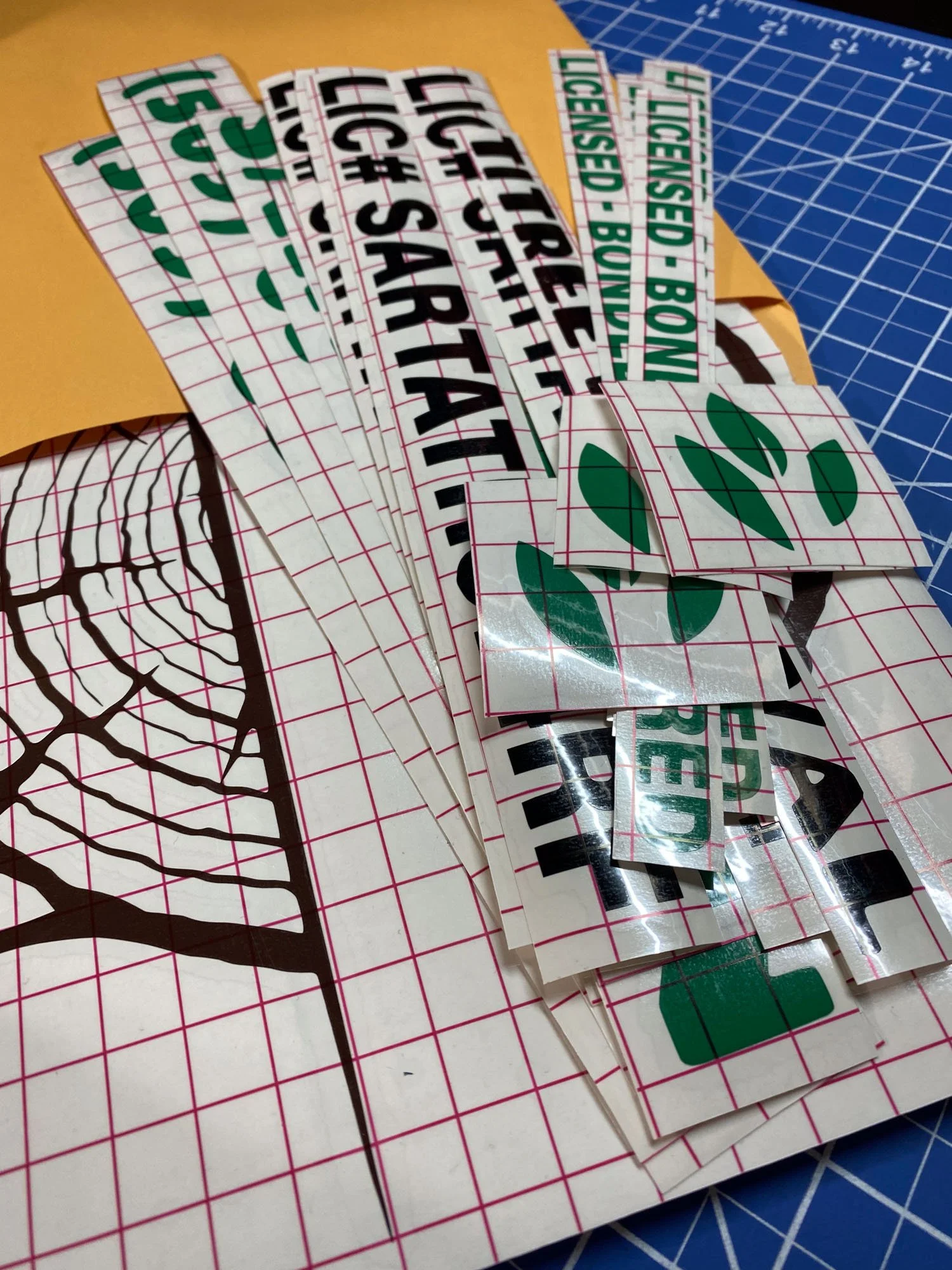 Collection of decal or sticker sheets with various printed designs and text, laid out on a cutting mat and paper surface.