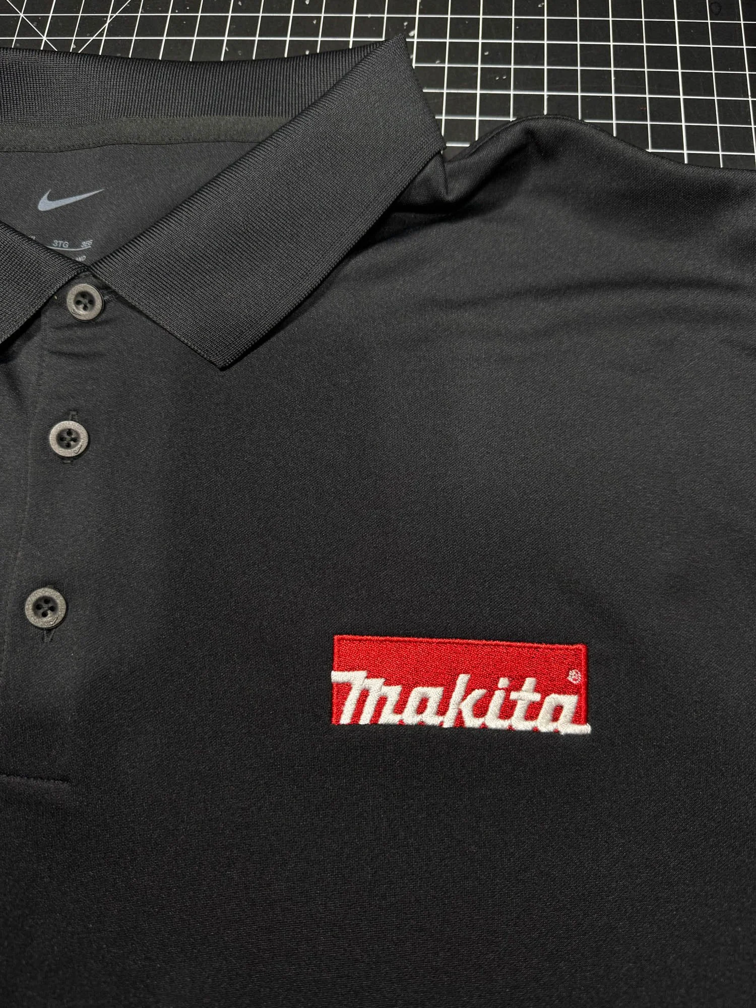 A black collared polo shirt with a red and white 'Makita' logo embroidered on the left chest.