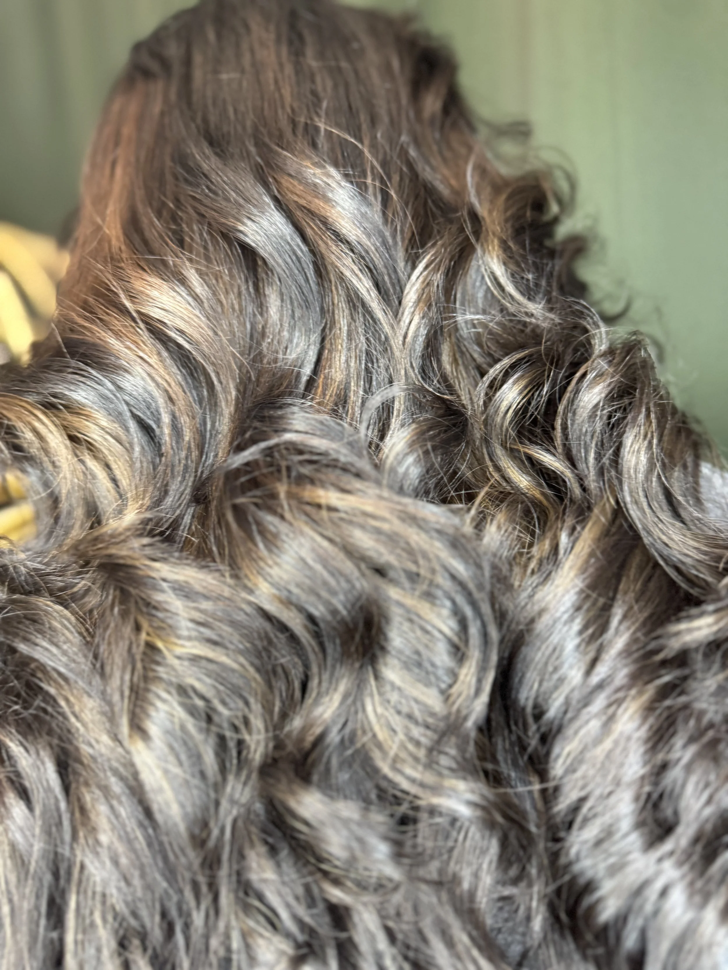 Close-up of curly, multi-toned brown hair with highlights.