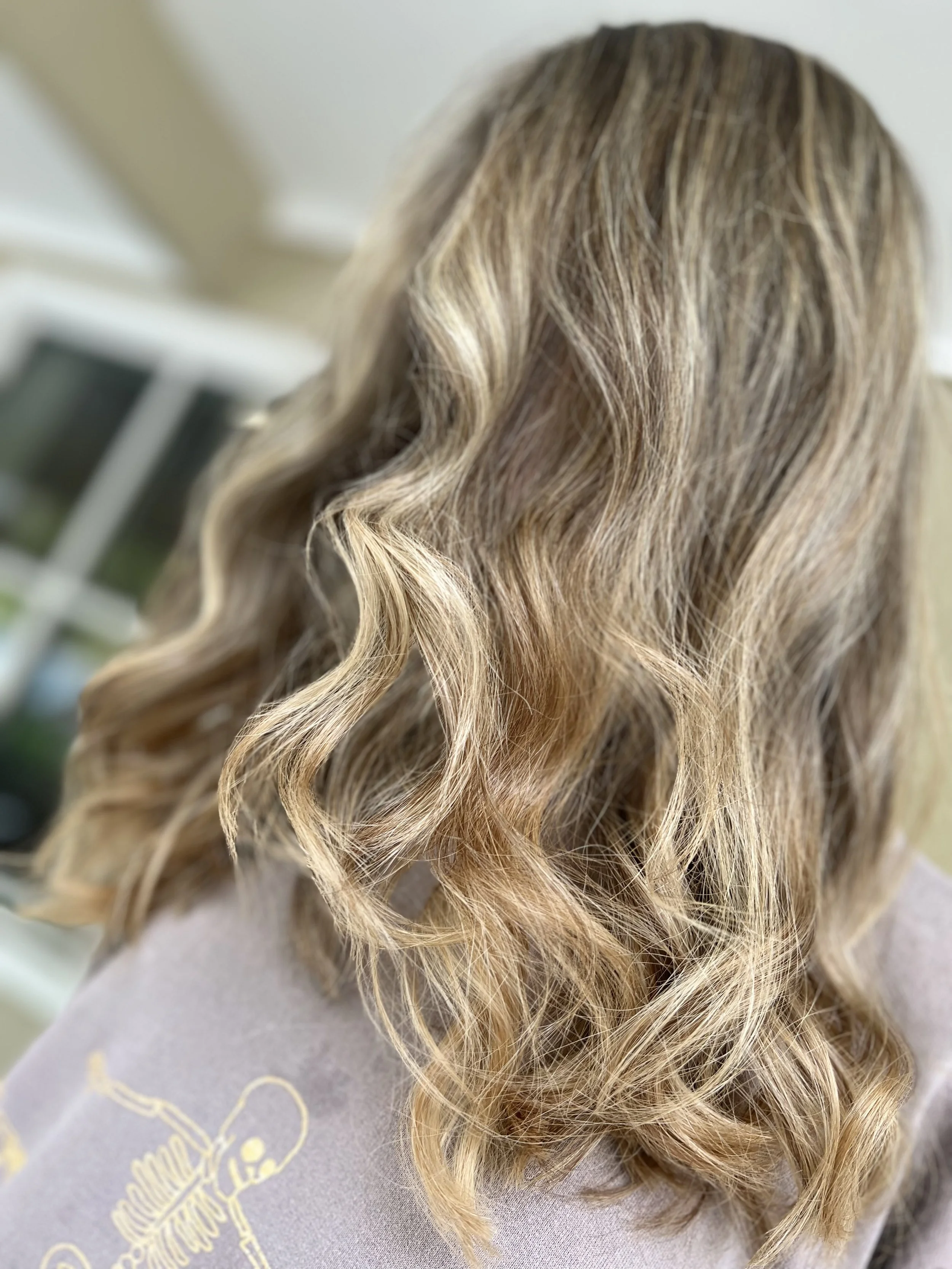 Close-up of wavy blonde hair with highlights.