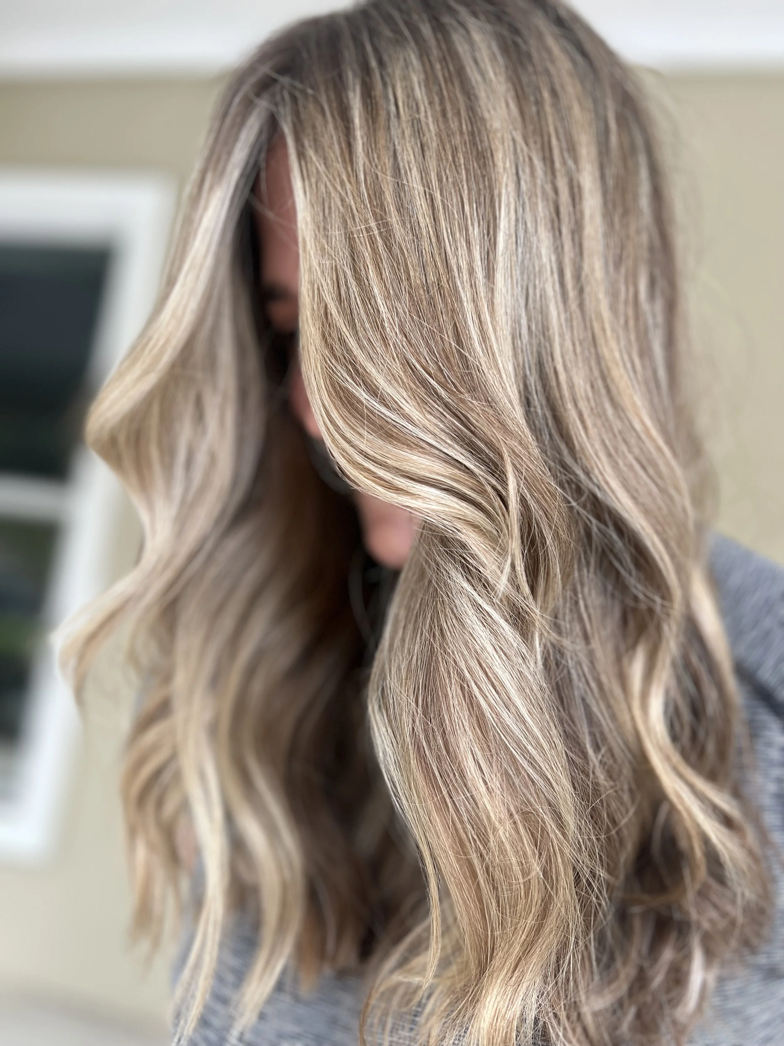 Close-up of wavy, blonde hair on a woman with a blurred background.