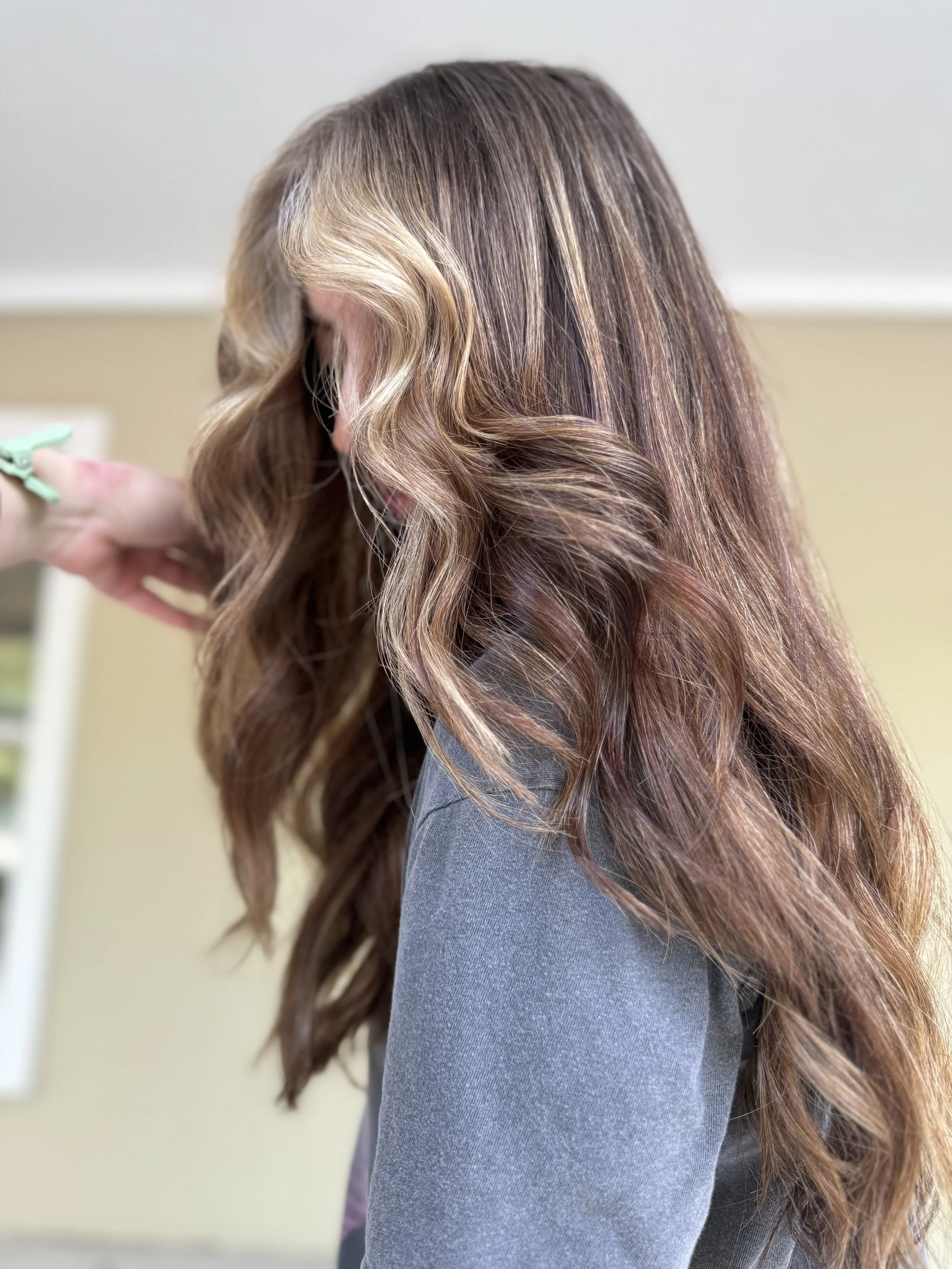 Close-up of a woman with long, wavy, caramel-colored hair.