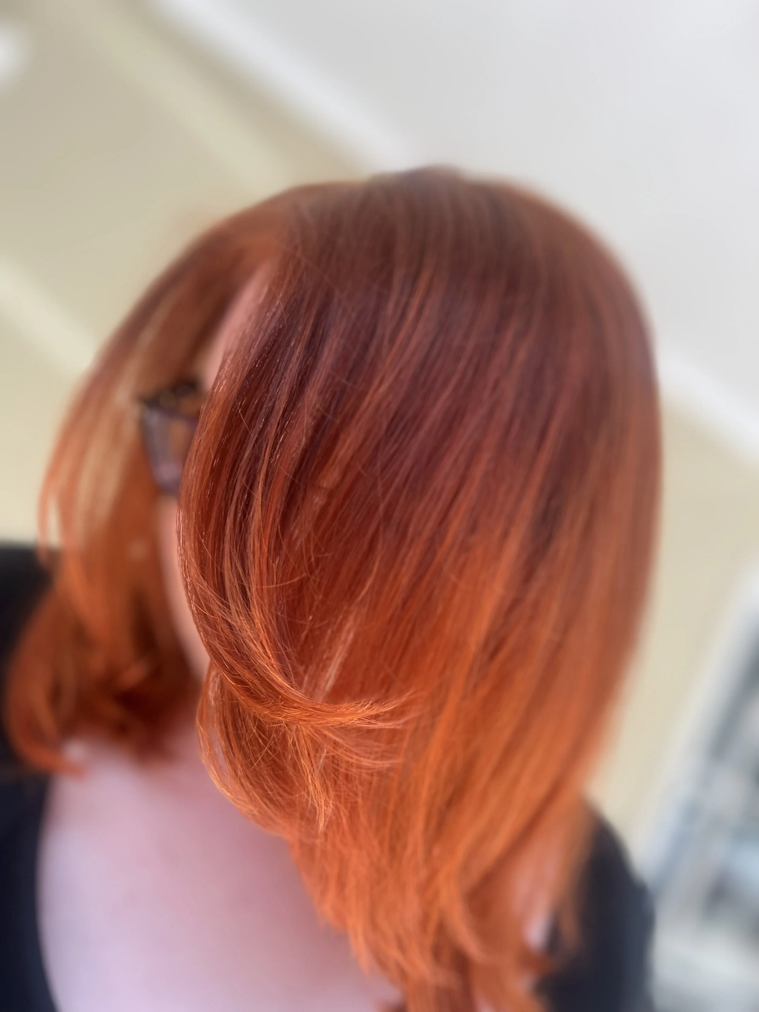 Close-up of a person with shiny, straight, vibrant red hair.