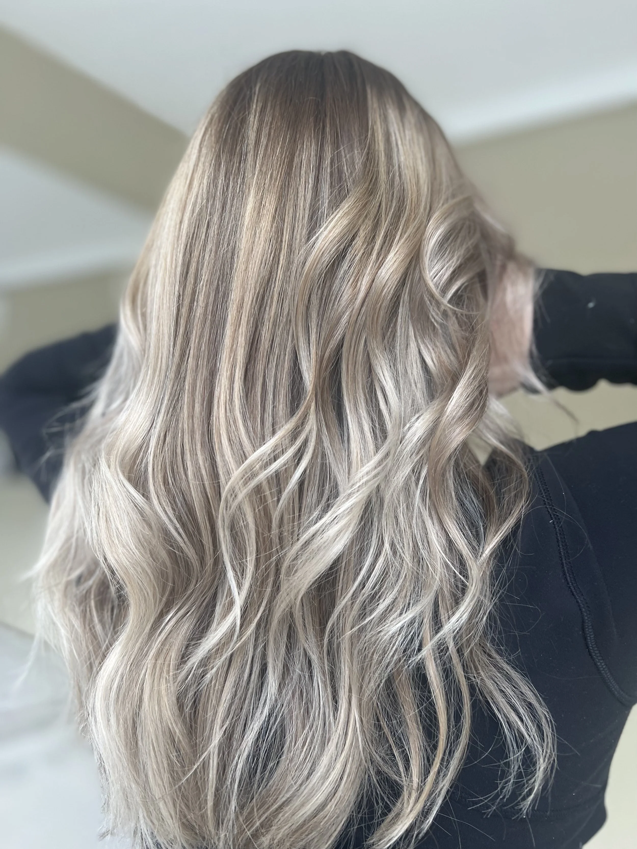 Long, wavy blonde hair with darker roots and lighter, highlighted ends.