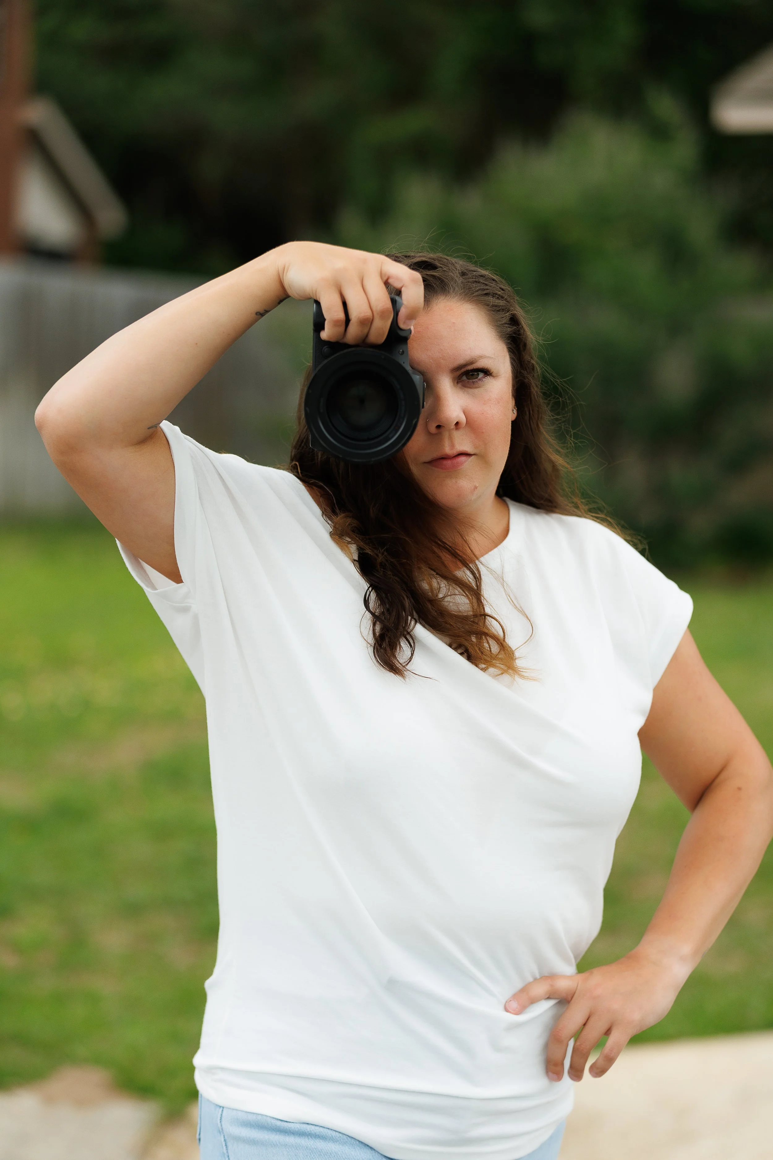 Madison Anderson, owner and lead photographer of Dark Room Boudoir, holding a camera in her Gulf Breeze photography studio.