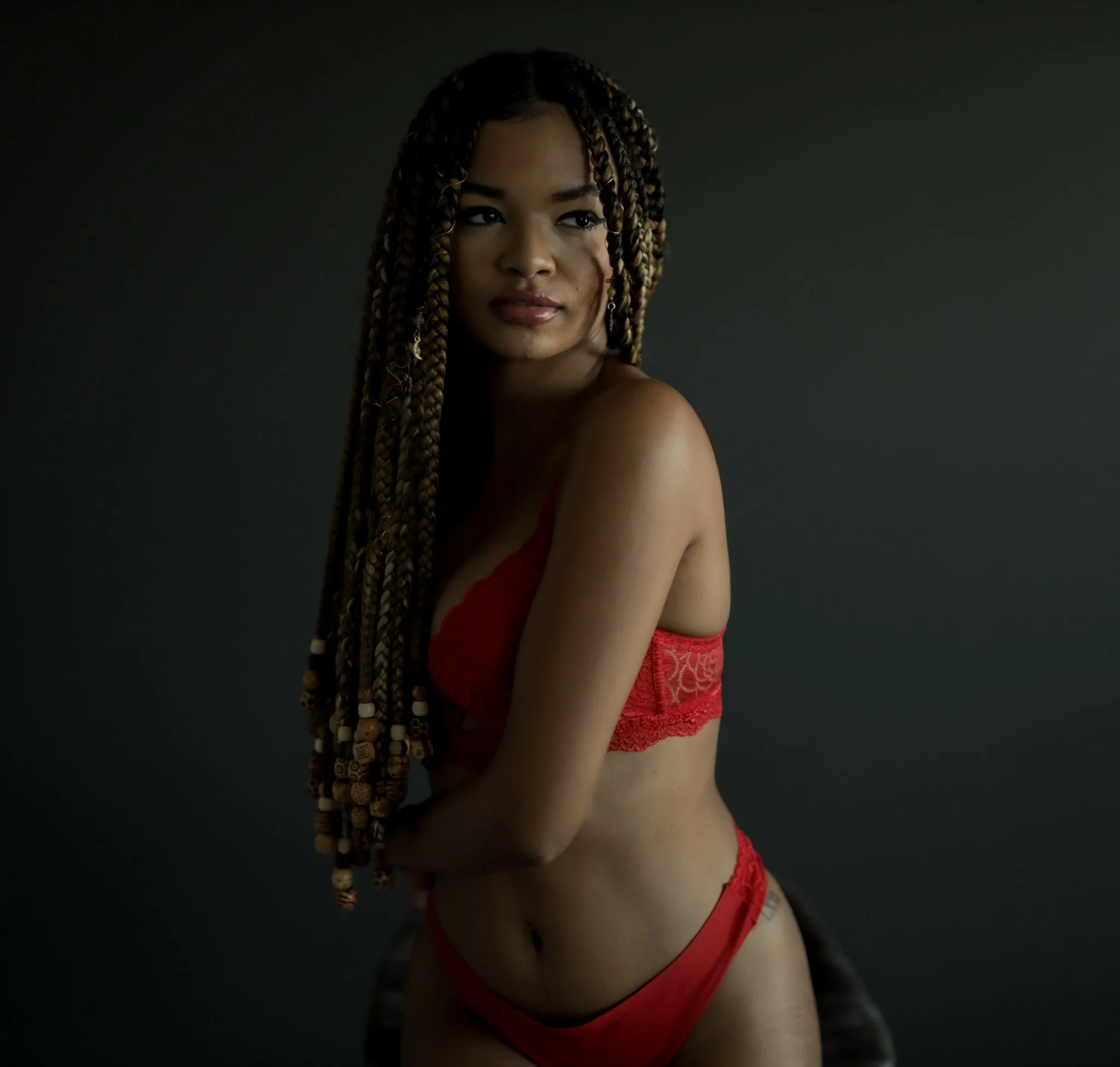 Confident woman posing in red lace lingerie during a professional boudoir transformation at Dark Room Boudoir.