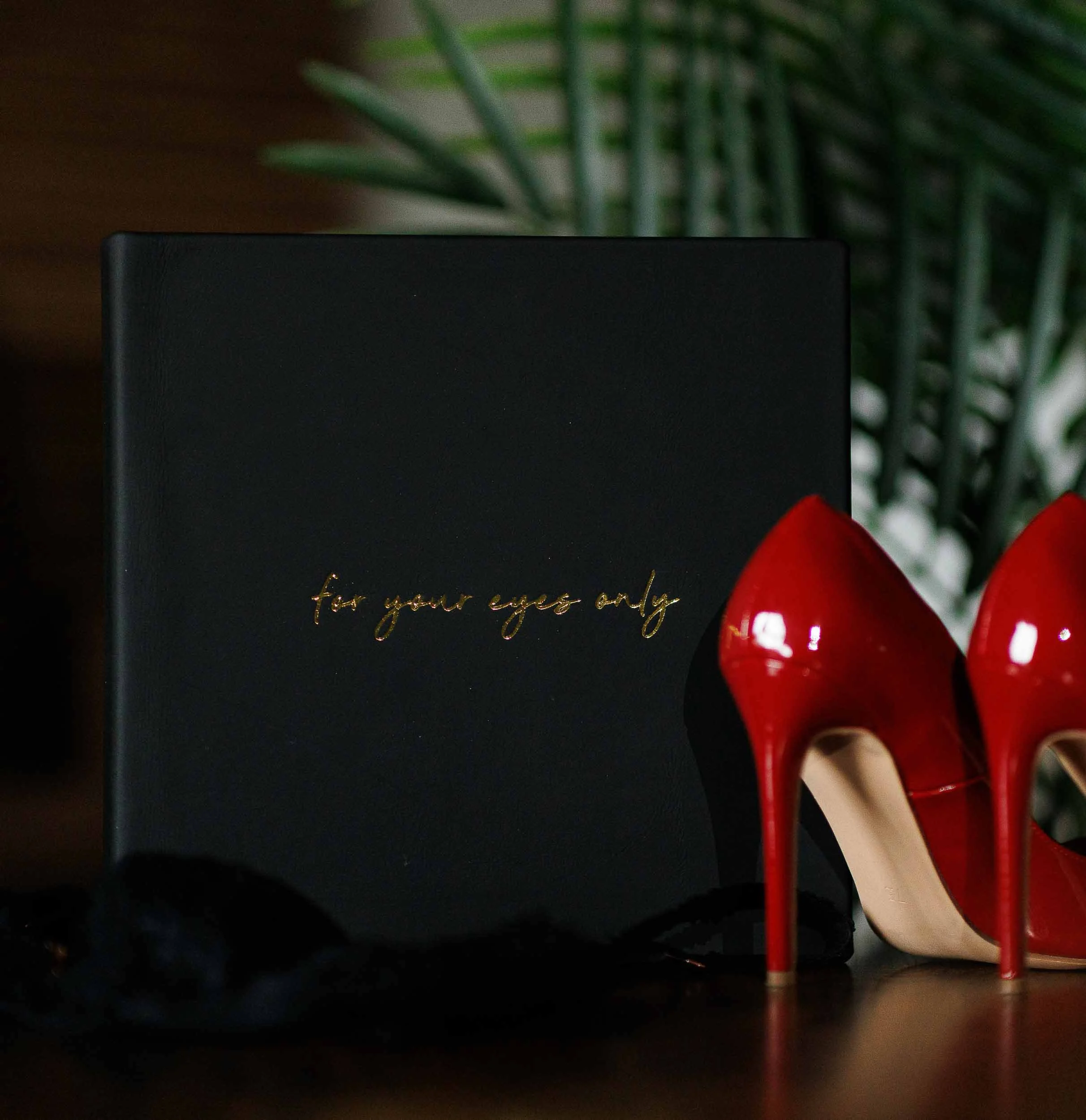 Custom heirloom boudoir album with gold foil detailing and a red luxury heel at Dark Room Boudoir.