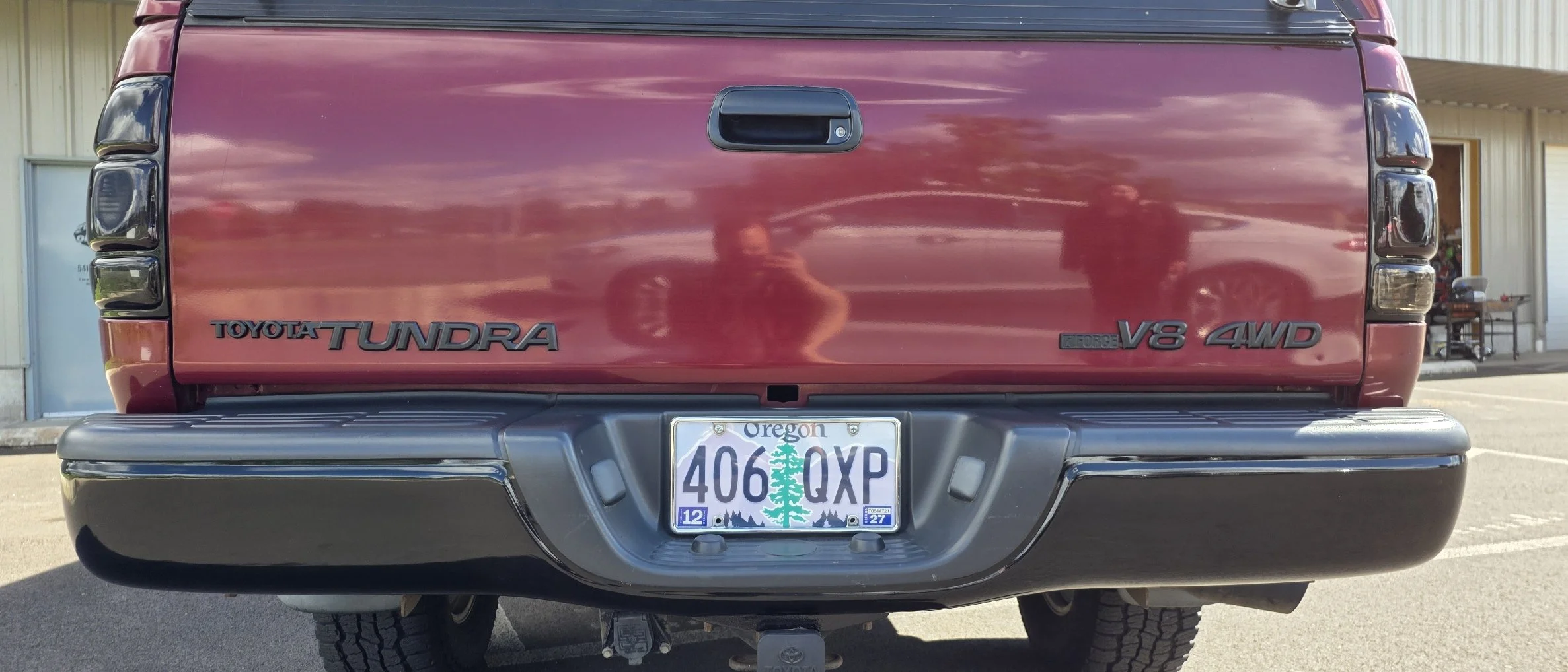 Rear view of a red Toyota Tundra pickup truck with Oregon license plate, showing badges for V8 engine, 4WD, and Toyota Tundra.