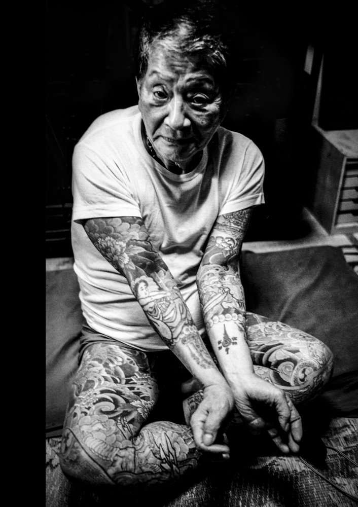 Black and white portrait of a seated and heavily tattooed Yakuza member.