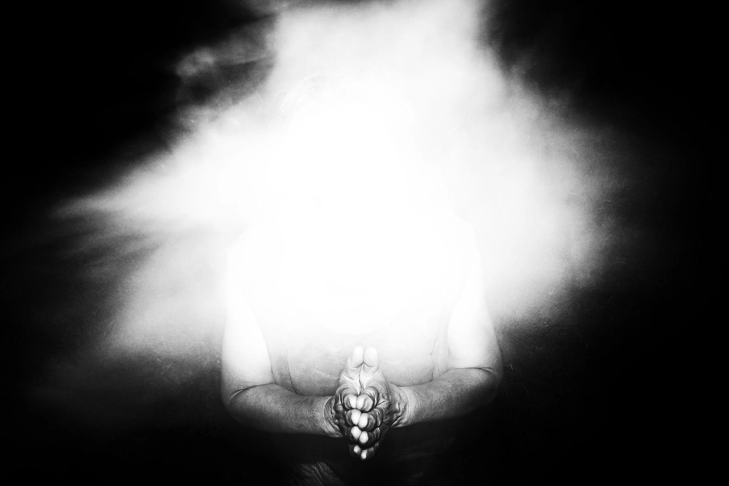 Black and white photo of an anonymous figure behind a flash of light.
