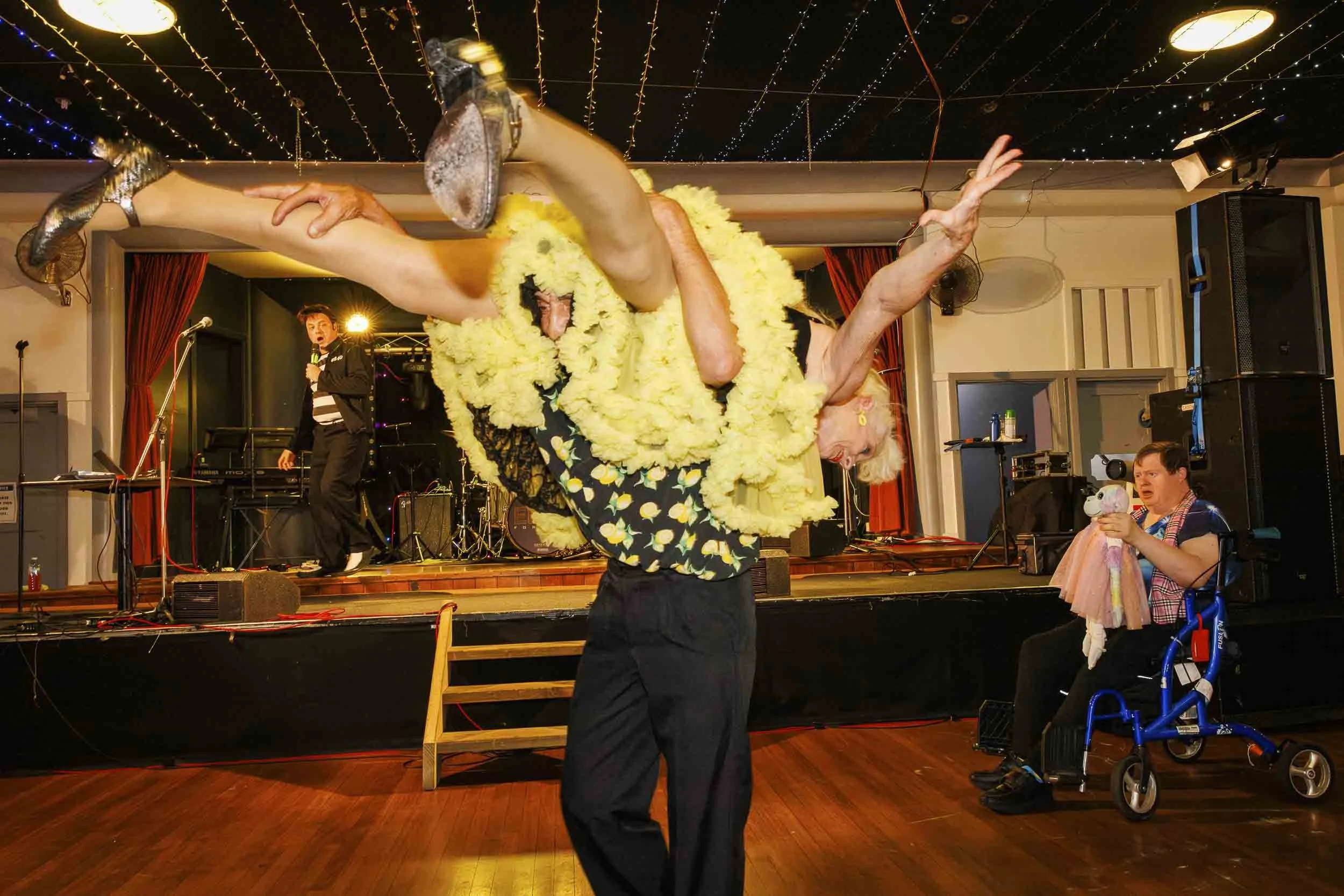 Elderly gentleman lifts his female dance partner  onto his shoulders while ballroom dancing.