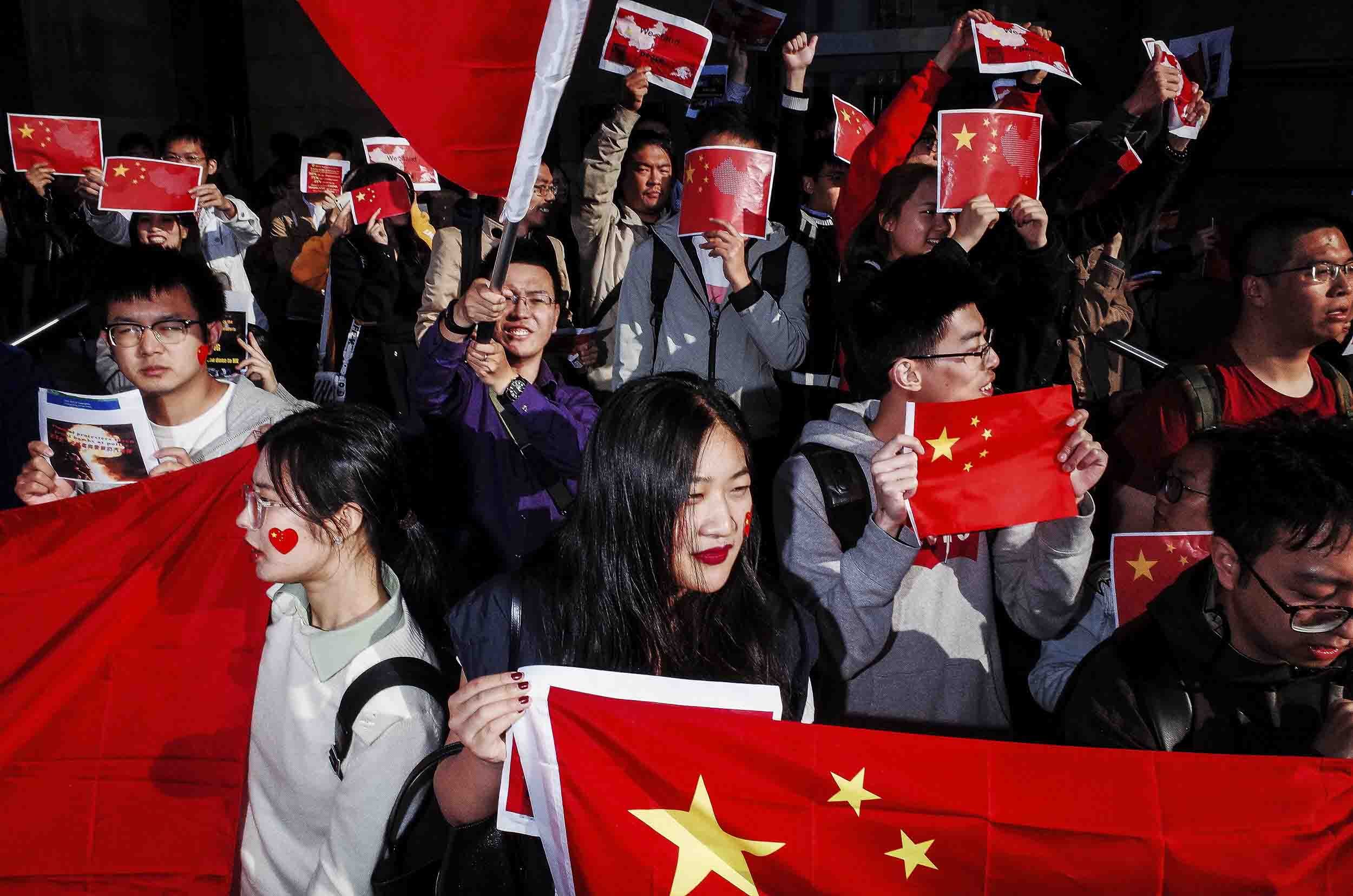 A group of Chinese holding flags and with red love hearts painted on their face.