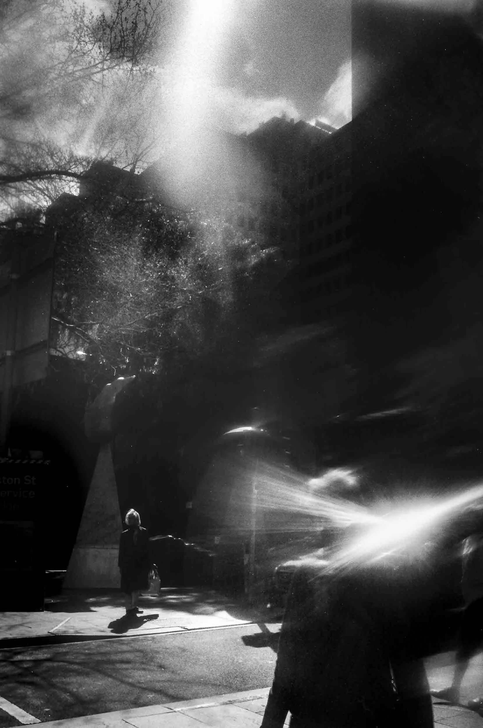 Black and white street photography of people walking in a city with light-leaks.