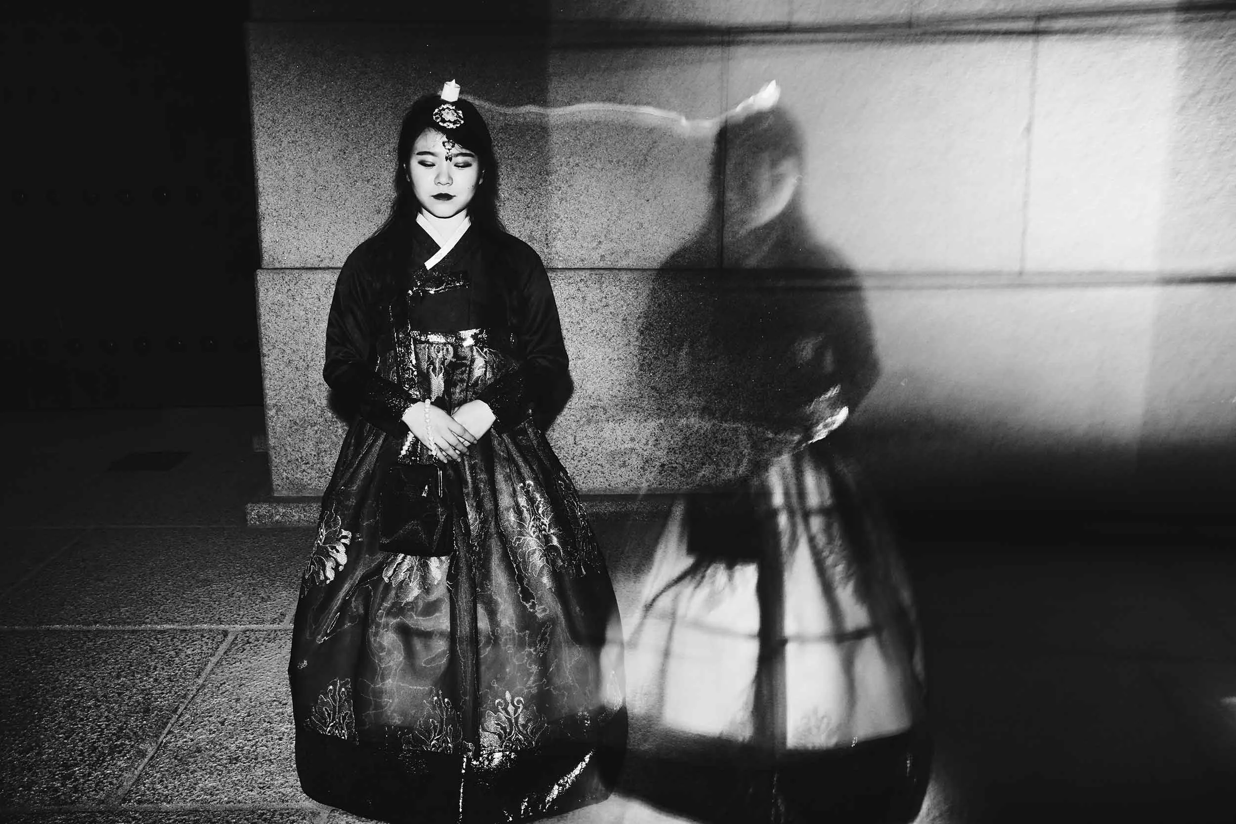 Black and white double exposure photograph of a South Korean woman standing still.