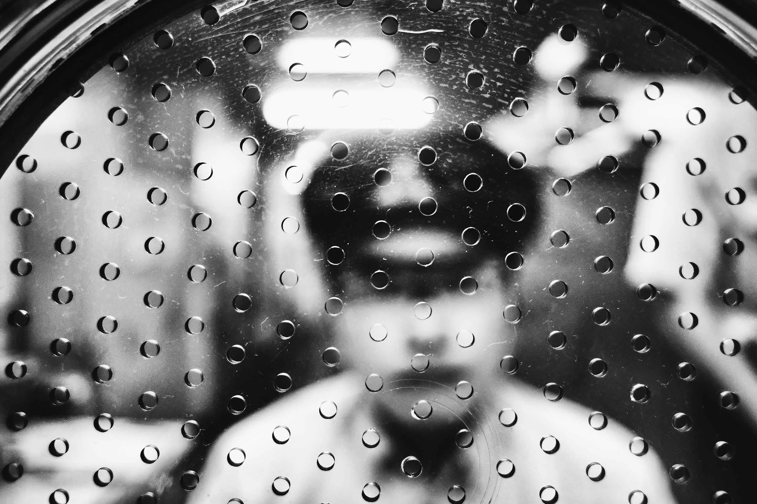 Black and white photo of an out of focus ticket collector sitting inside a Tokyo Metro ticket booth.