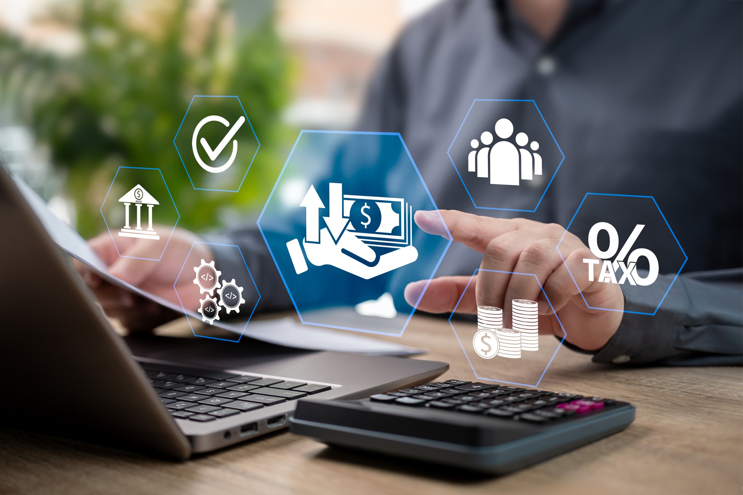 Person using a laptop and calculator with digital financial icons, including money exchange, taxes, and financial growth symbols, overlaid in holographic style.