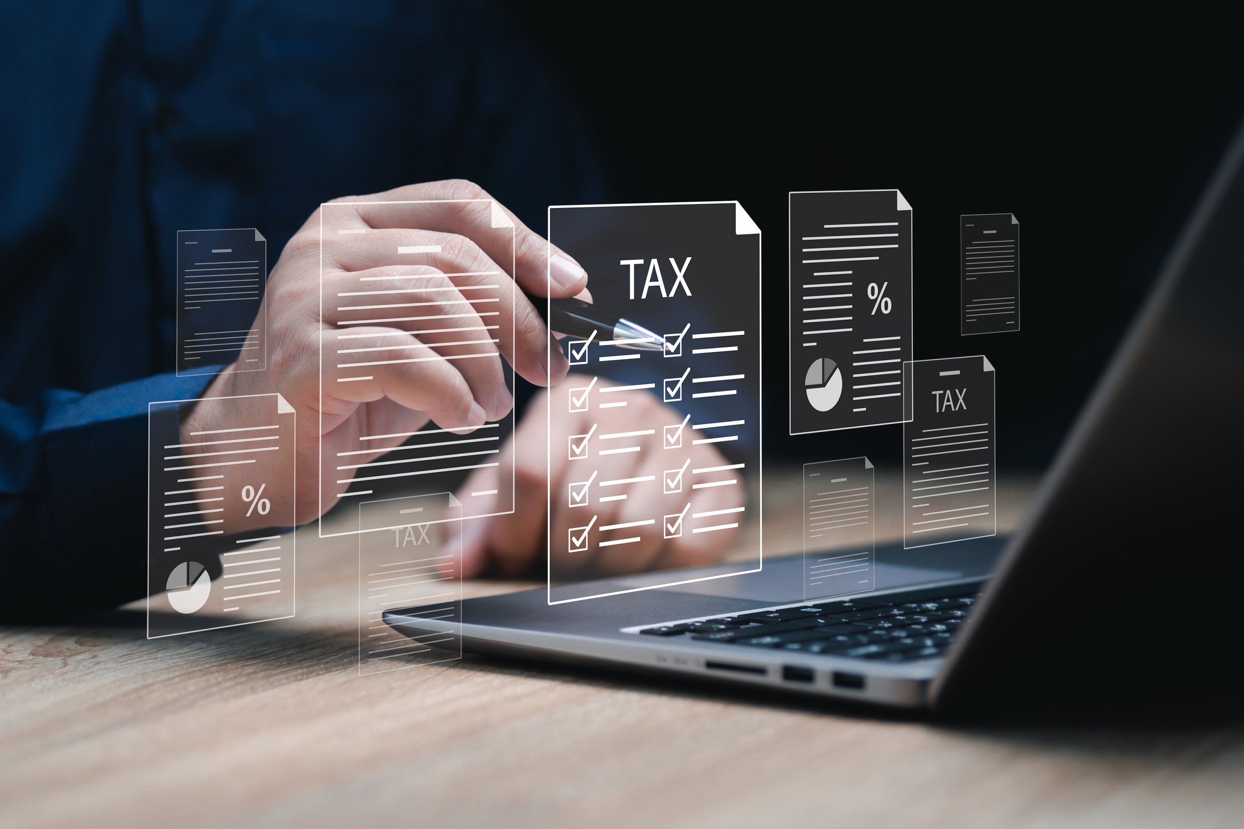 A person using a stylus to check off boxes on a virtual tax document overlay on a laptop.