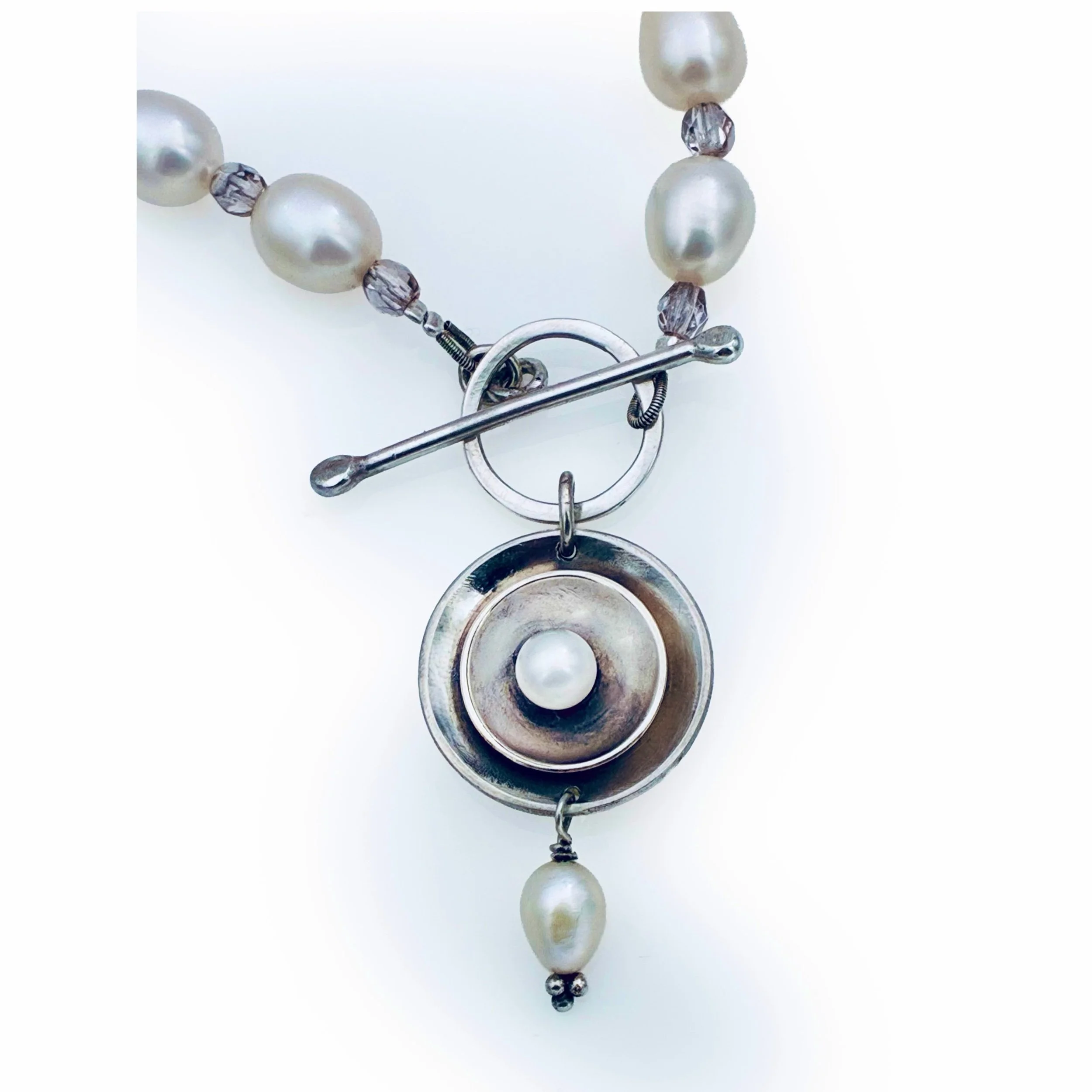 Close-up detail of the handcrafted sterling silver toggle clasp on the pearl necklace.