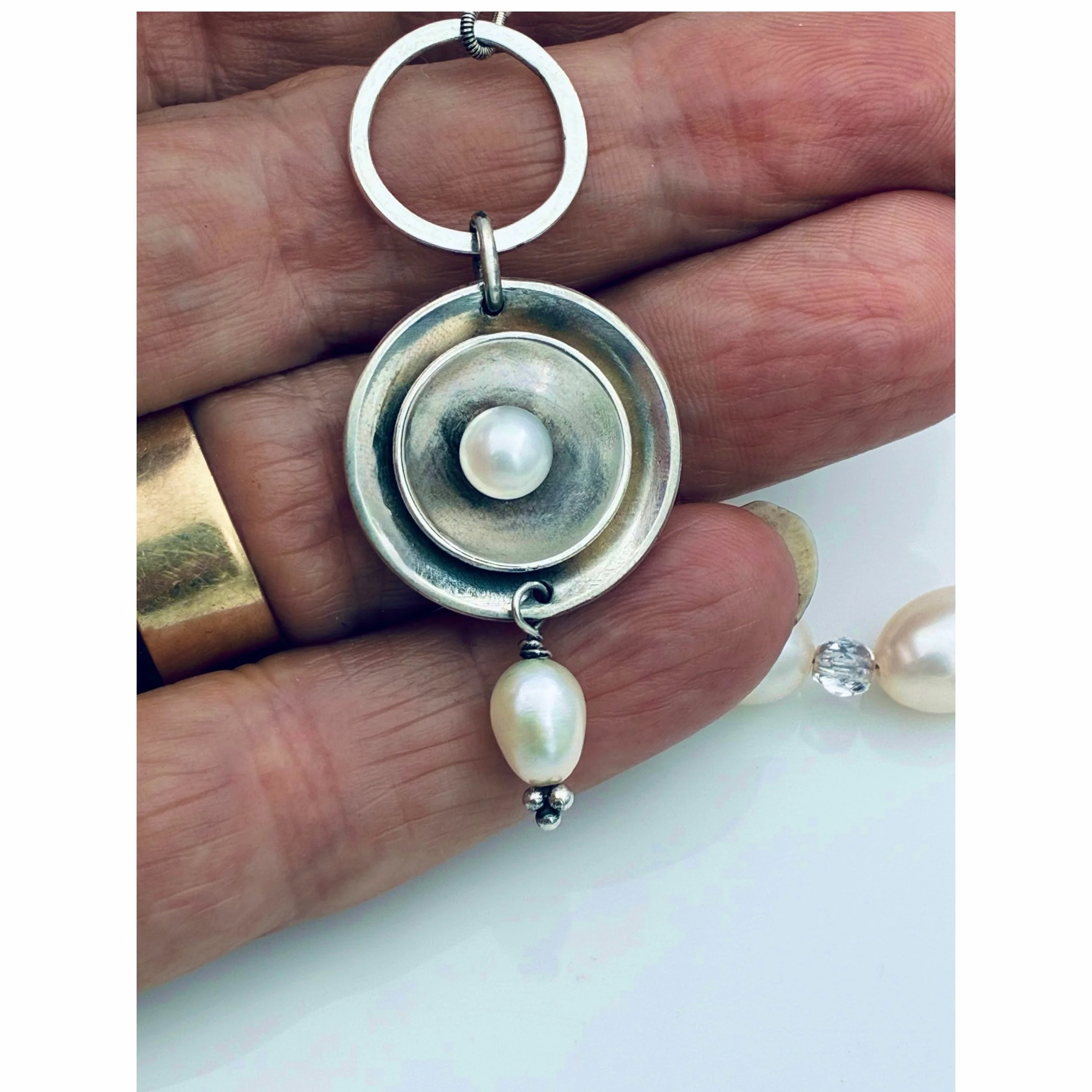 Close-up detail of the handcrafted sterling silver toggle clasp on the pearl necklace showing scale.