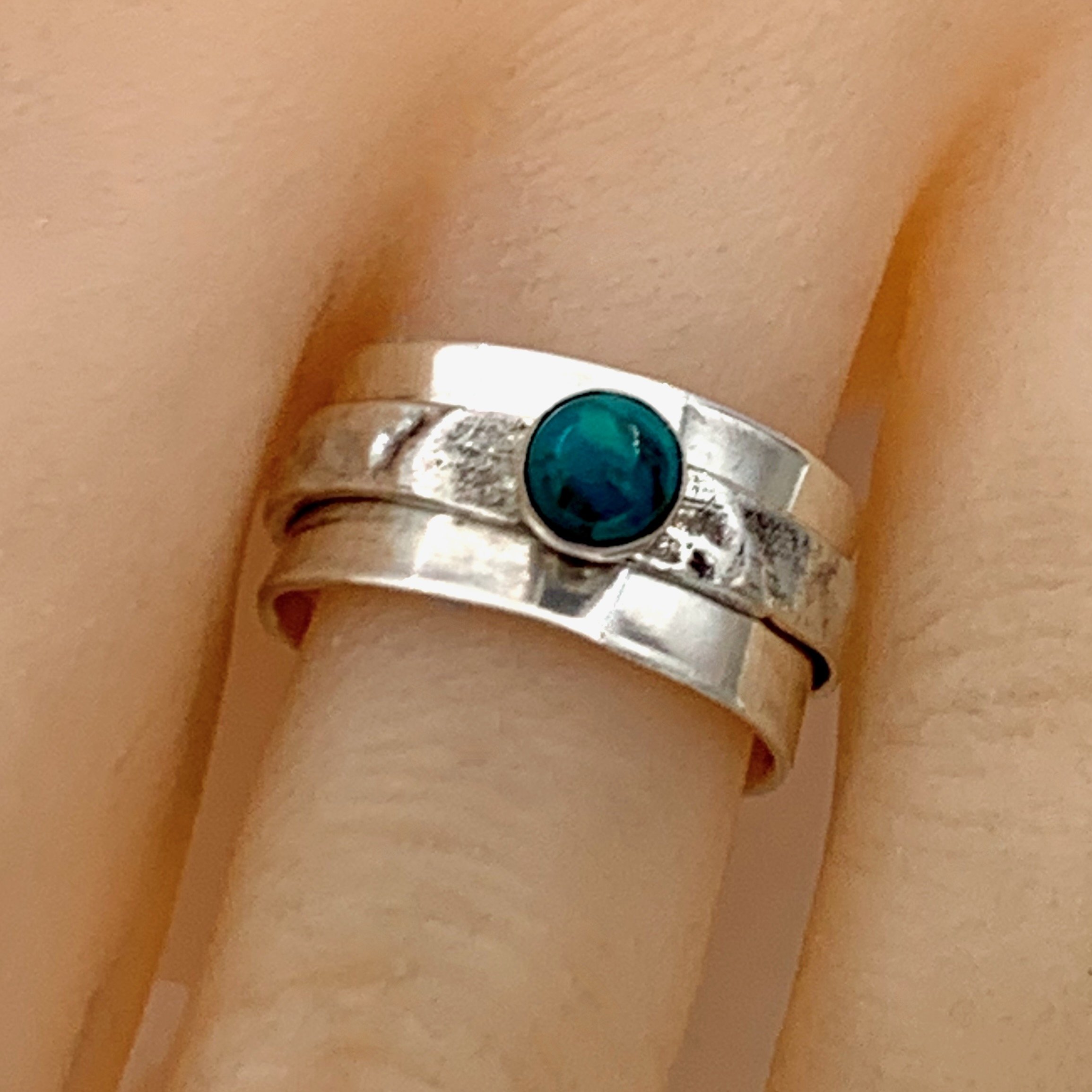 One-of-a-kind handcrafted sterling silver spinner ring featuring a chrysocolla cabochon with textured bands.