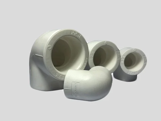 Four PVC pipe fittings of various sizes against a light background.