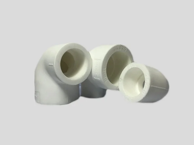 Three white PVC pipe fittings on a plain background