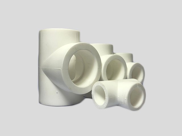 Assorted white PVC pipe fittings on a plain background.