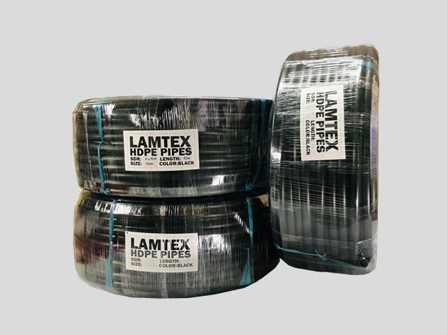 Three rolls of black HDPE pipes wrapped in plastic on a gray background.