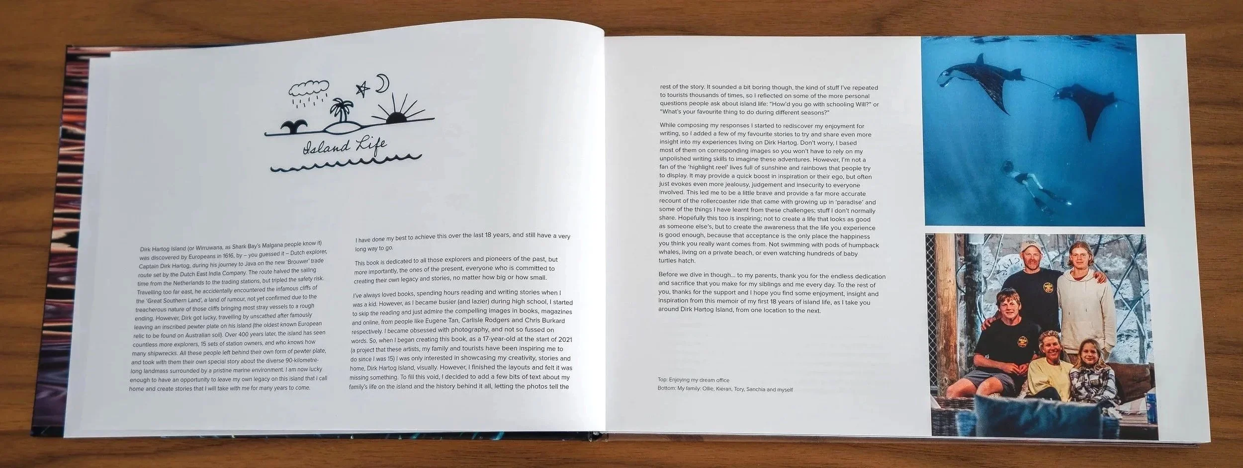 Open travel book featuring hand-drawn island scene sketch and colorful photographs including an underwater scene with dolphins and a family portrait in a snowy setting.