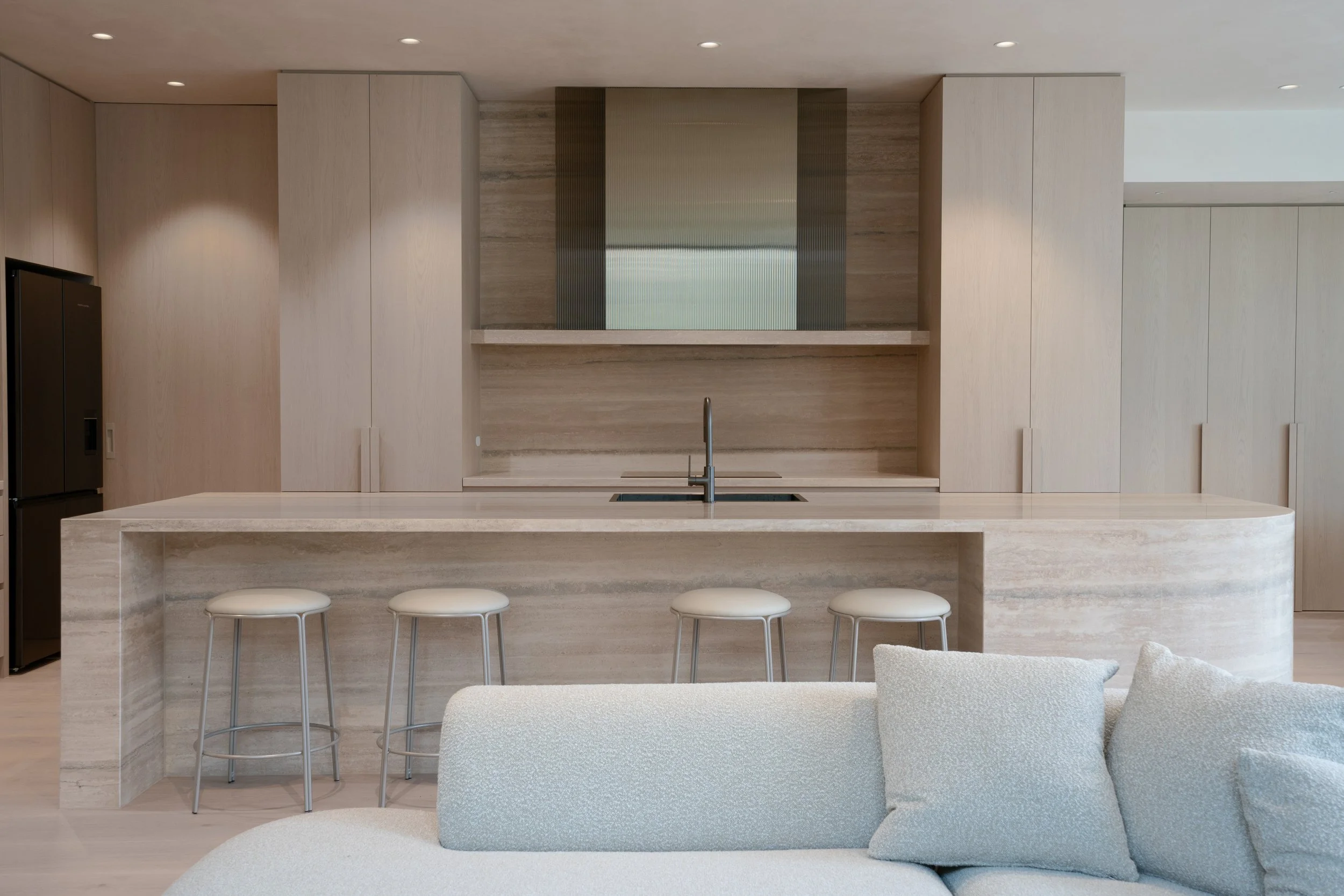 Travertine kitchen island with integrated joinery and fluted glass rangehood design, Melbourne